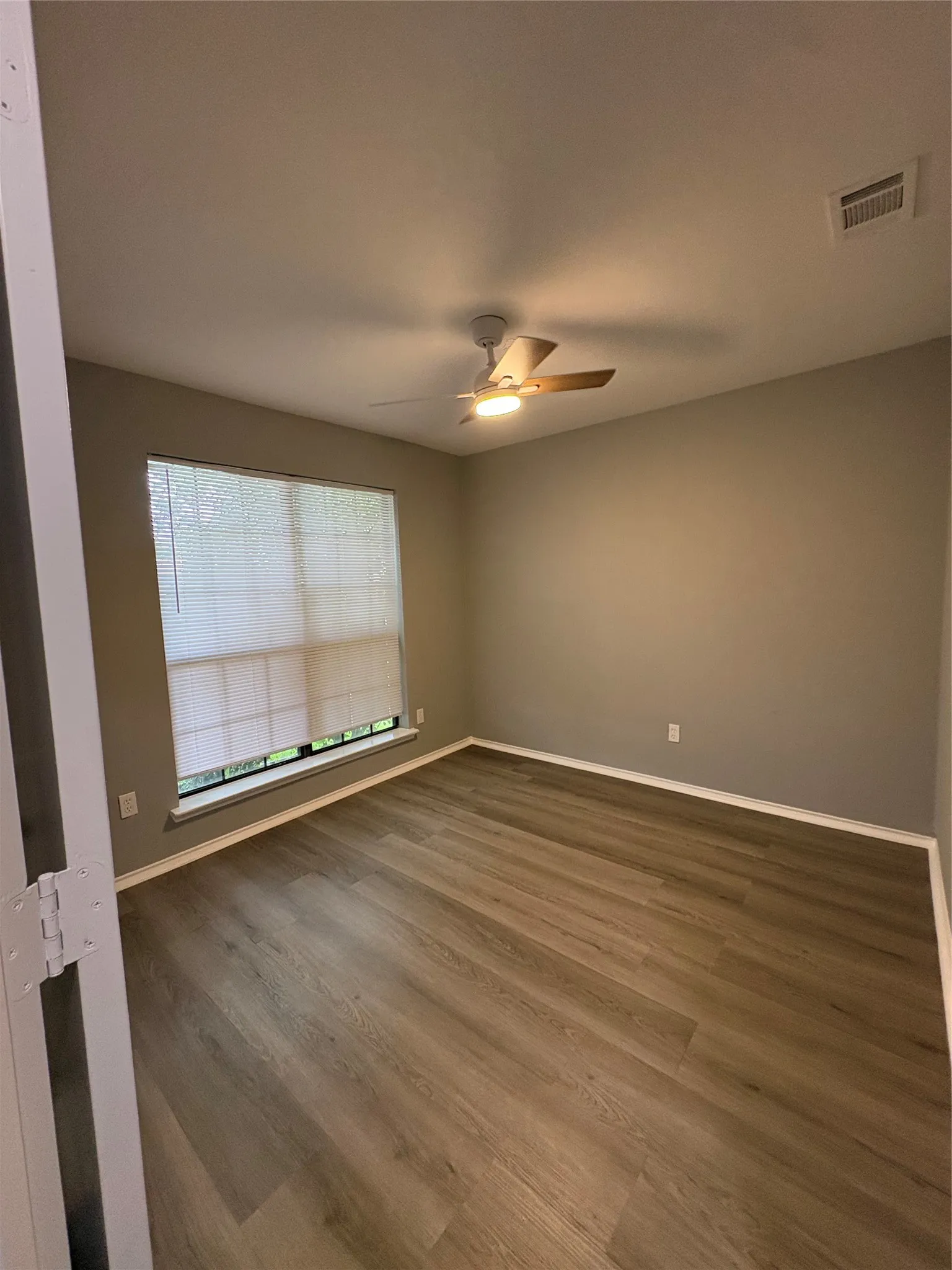 Wood-finish flooring throughout, complemented by a ceiling fan with integrated lighting