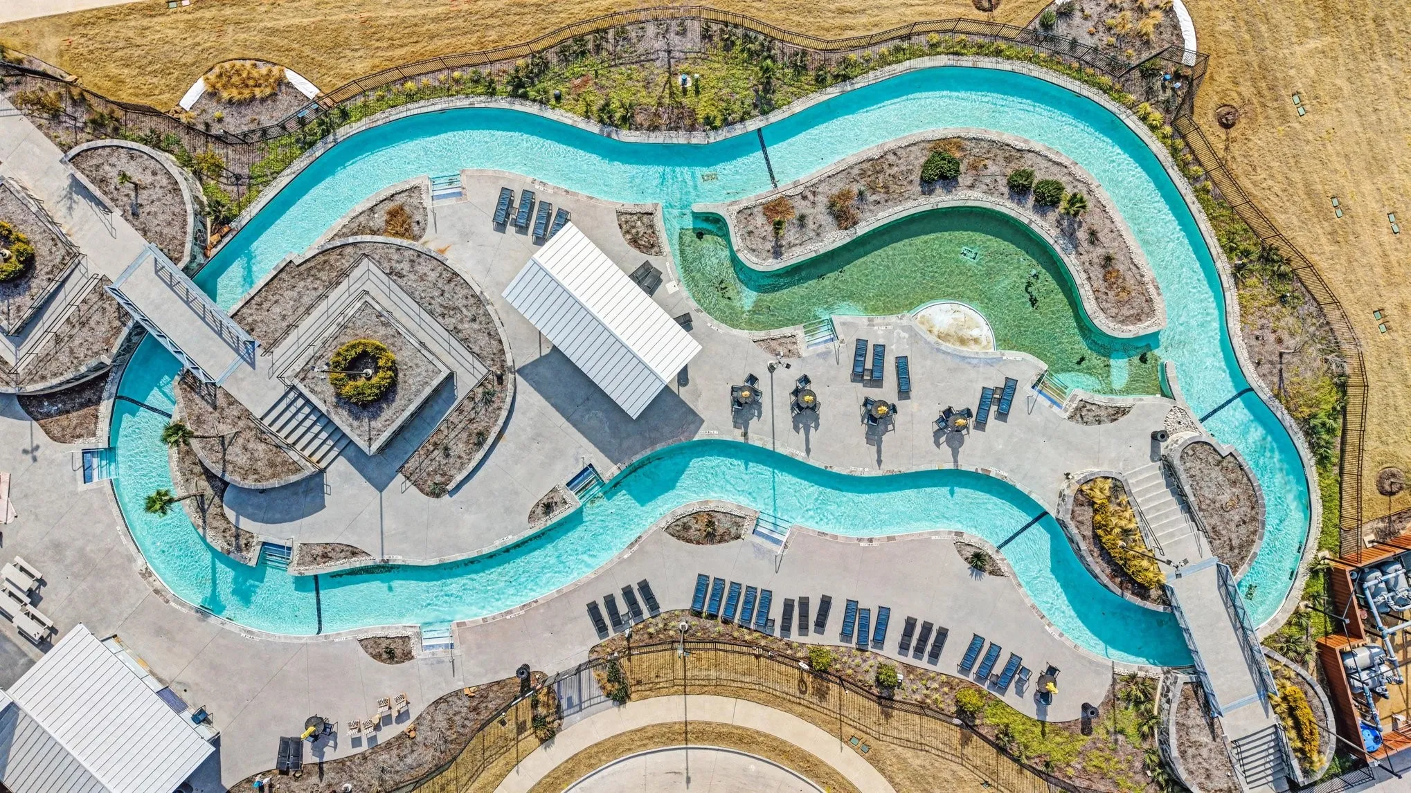 Expansive aquatic amenity featuring a winding waterway, multiple bridges, two shaded structures, and integrated lounge areas