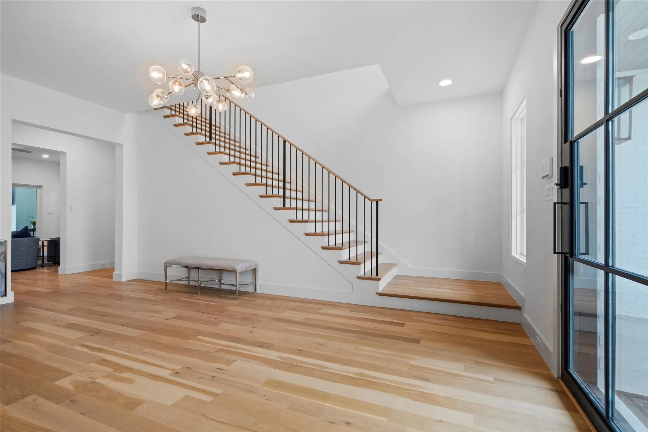 Large entry area, with wood stairs and a unique chandelier.