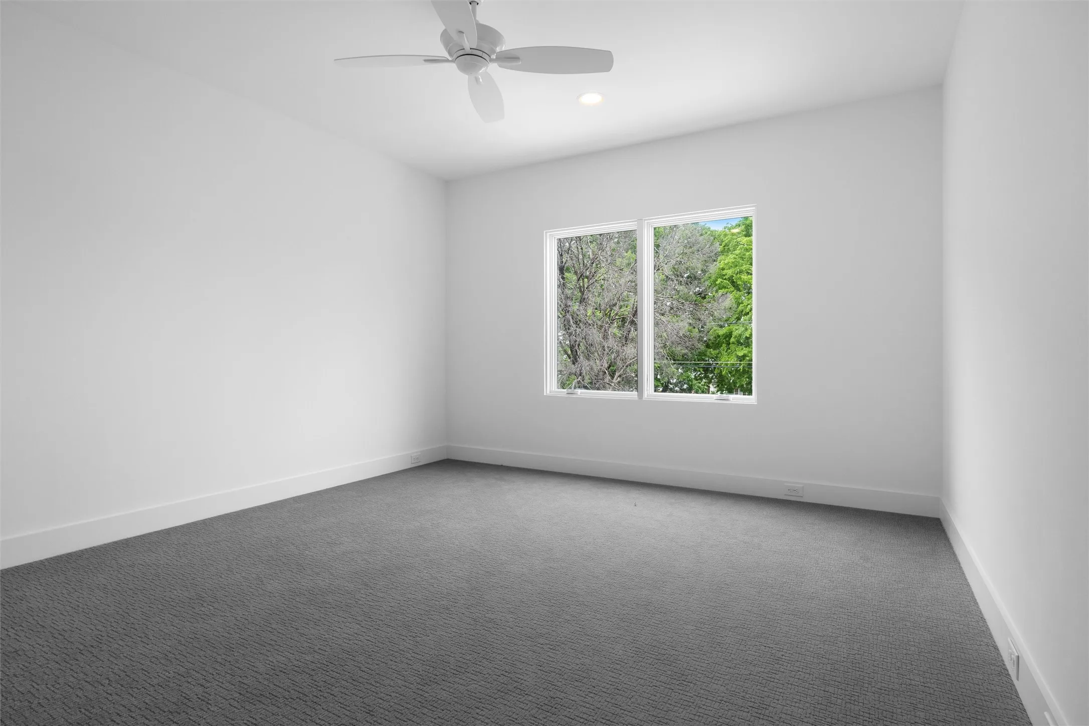 One of three bedrooms on the second floor, featuring dark colored carpet and ceiling fan with large window providing abundant natural light.  Overlooks pool area!