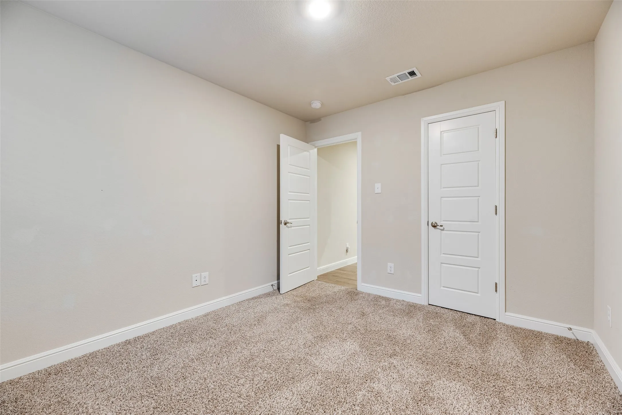 Carpeted flooring, light-toned wall paint, white trim, recessed lighting, and a five-panel interior door