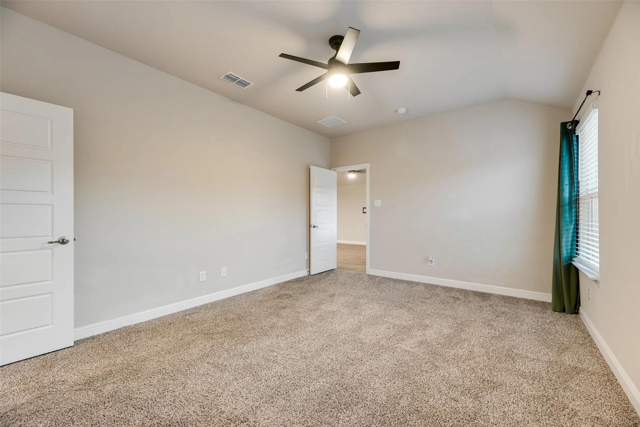 Carpeted room featuring a ceiling fan, vaulted ceiling, and white paneled doors