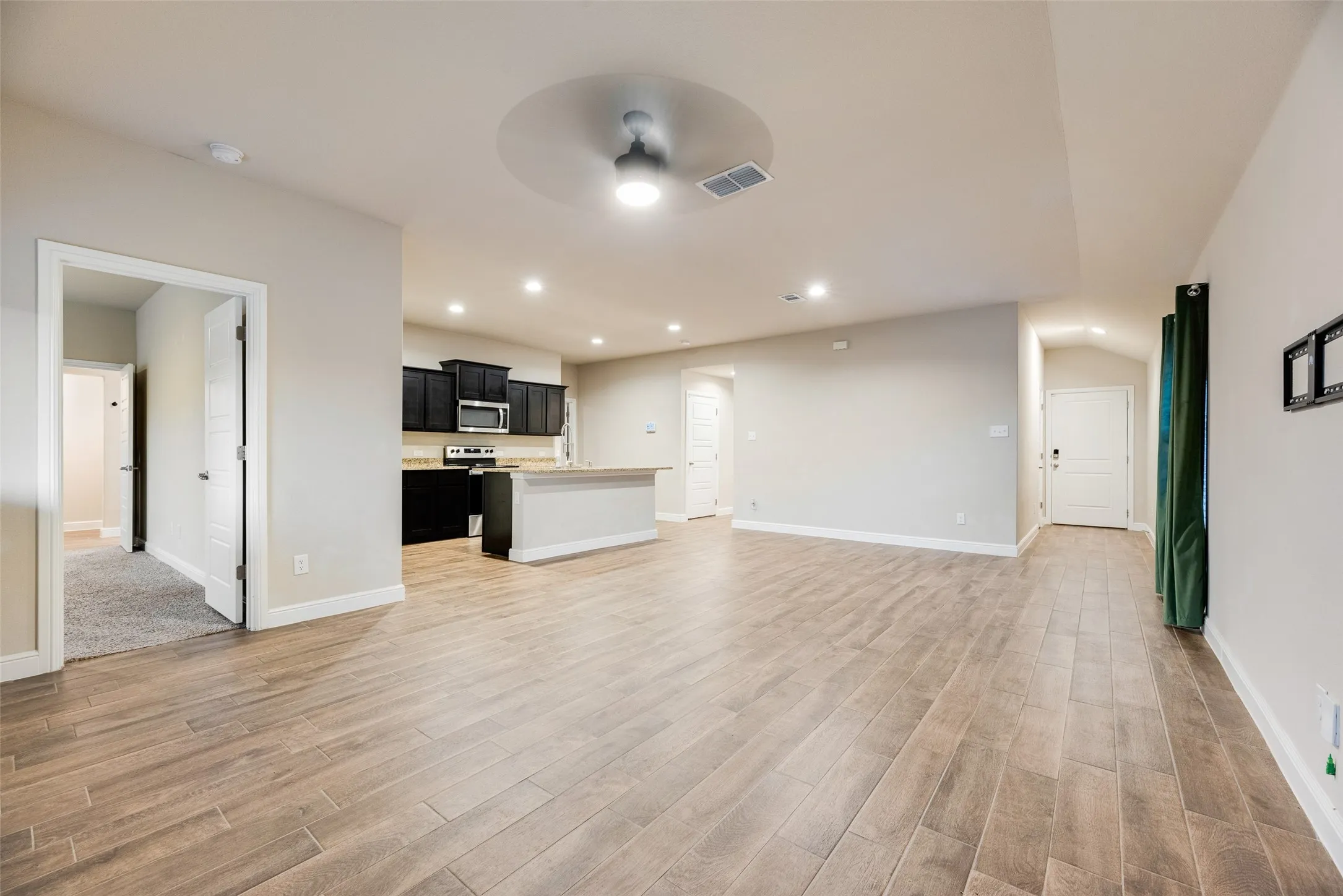 Open-concept living space with wood-look tile flooring, recessed lighting, and a contemporary ceiling fan