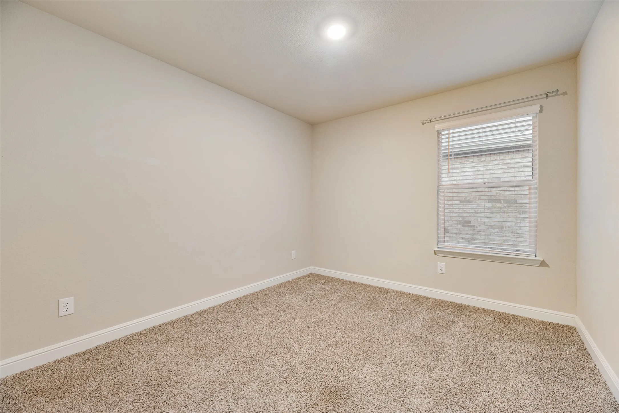 Neutral-toned walls, plush carpet, recessed lighting, and a window with blinds