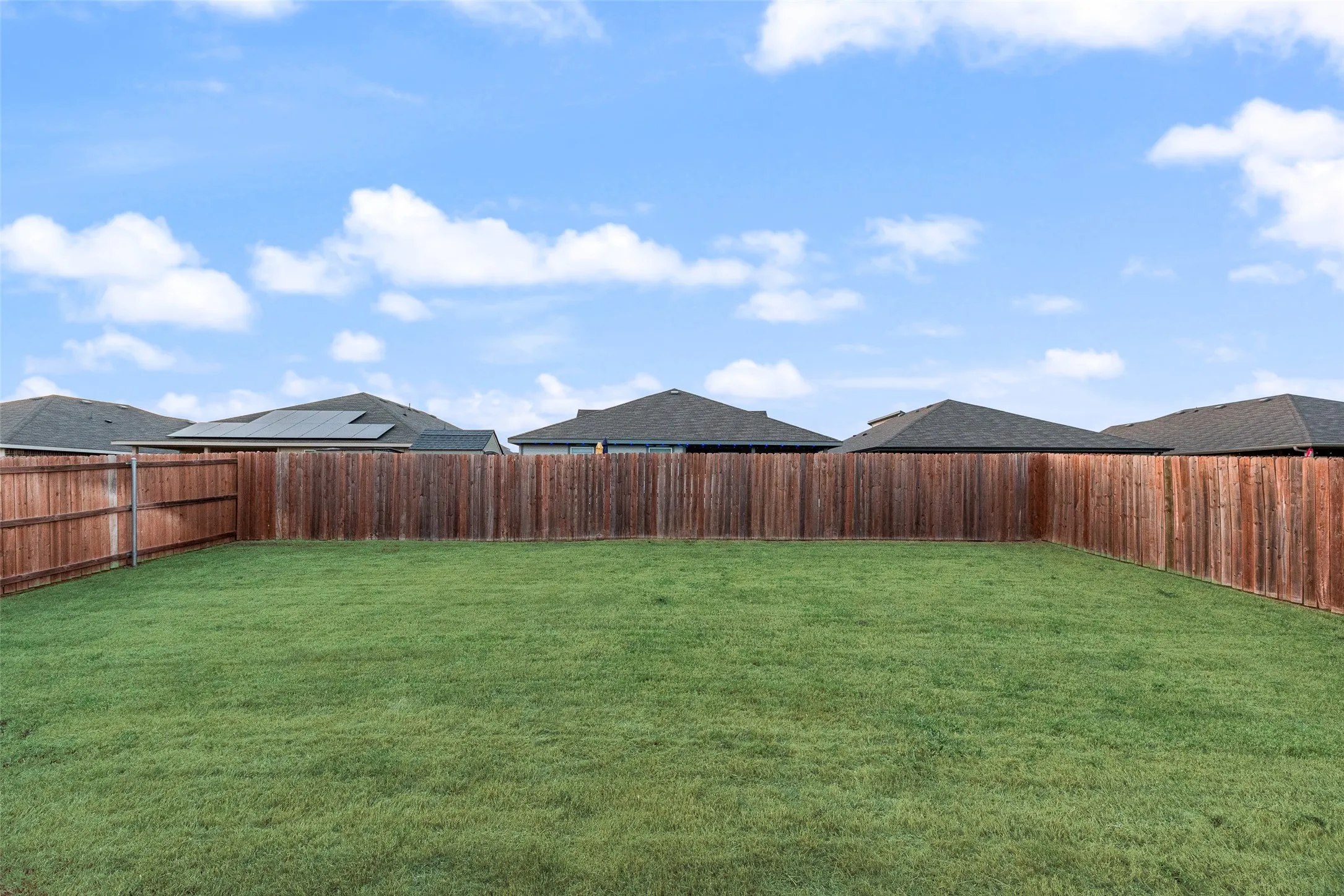 Expansive rear yard featuring a manicured lawn and a full privacy fence