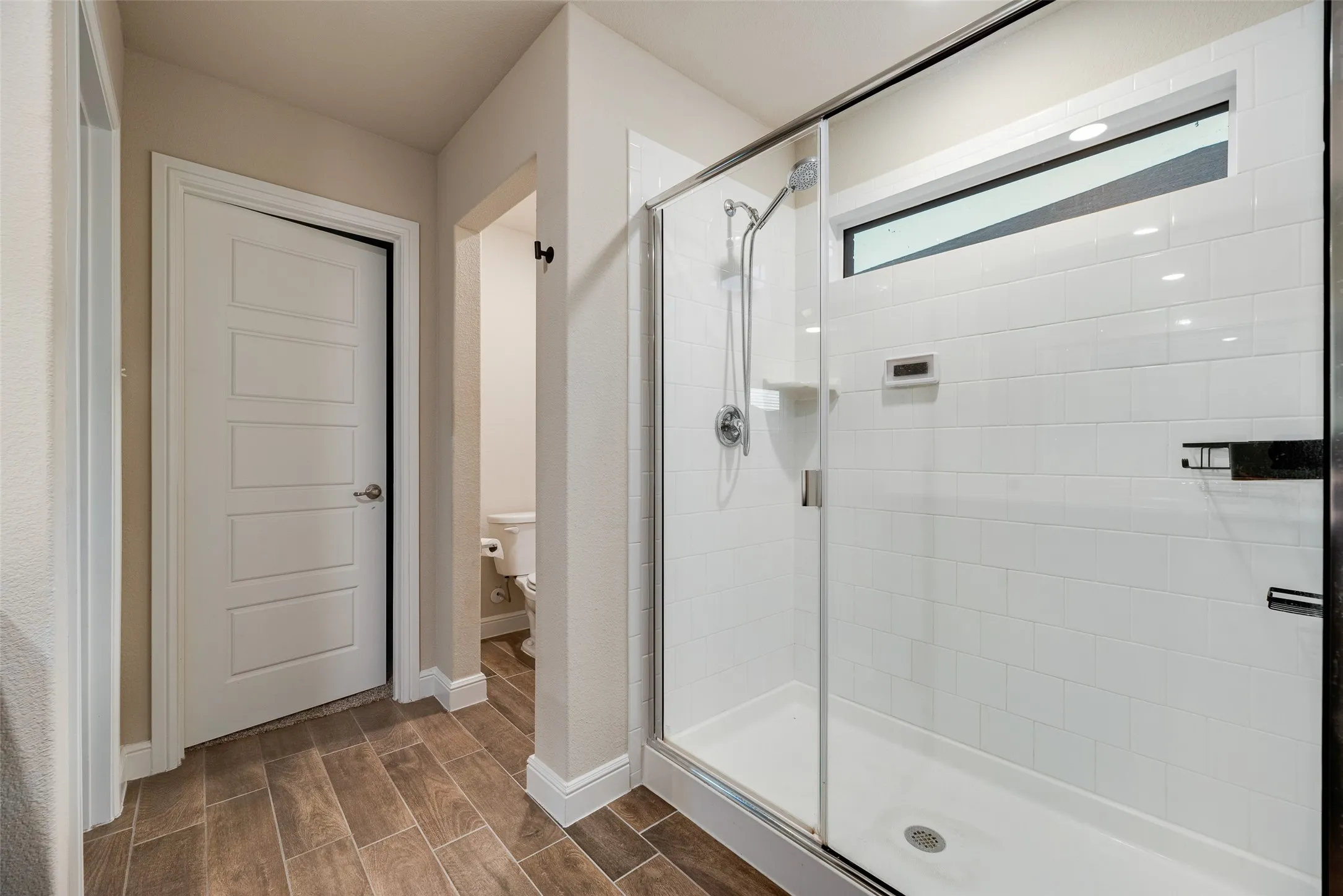Walk-in shower with clear glass enclosure and white subway tile surround