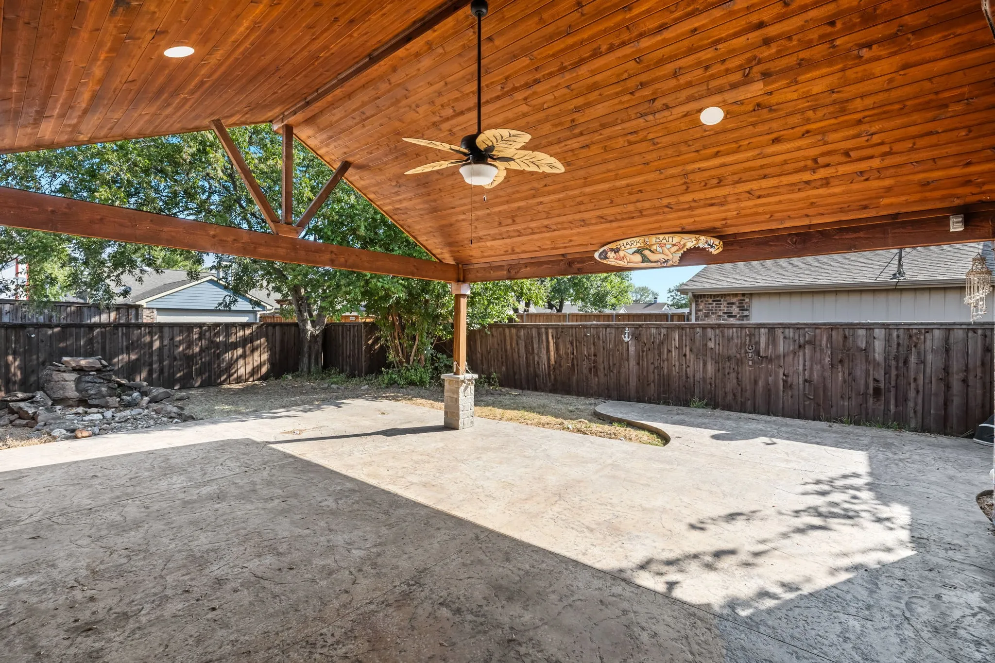 Expansive covered patio with a wood-planked ceiling, exposed wood beams, a ceiling fan. Don't miss the tranquil natural stone water fountain!