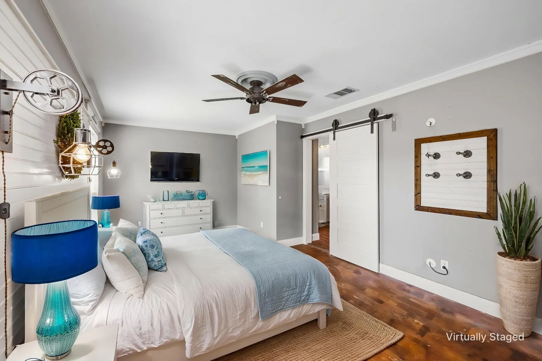 Virtually staged photo - Primary bedroom. Smooth stained concrete flooring, barn door entry to en suite, ceiling fan with integrated lighting, shiplap accent wall, and wall-mounted industrial-style lighting. Plenty of room for a quiet sitting area if desired.