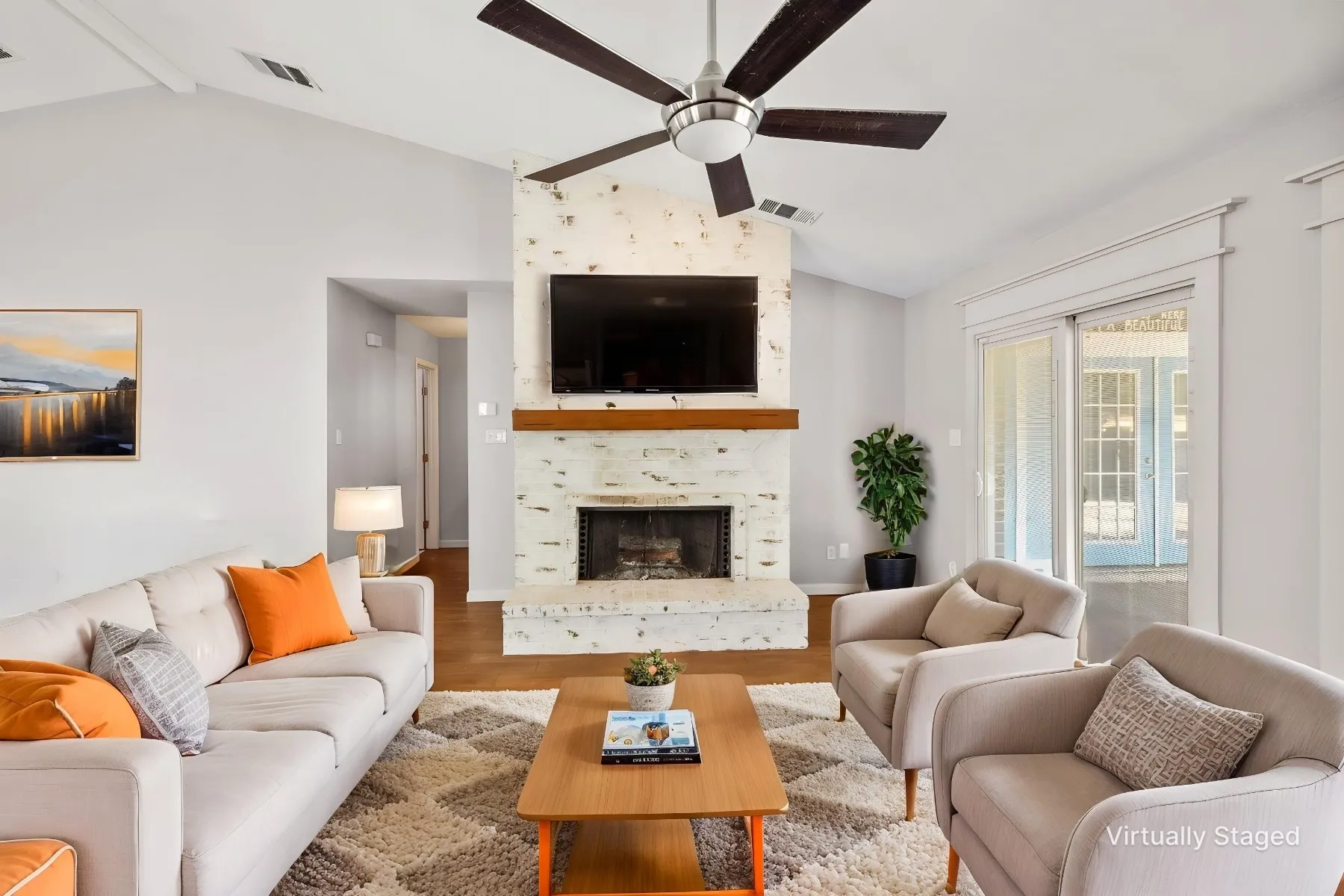 Virtually Staged photo - Living room with brick wood burning fireplace. Sliding glass door leads to oversized covered patio.