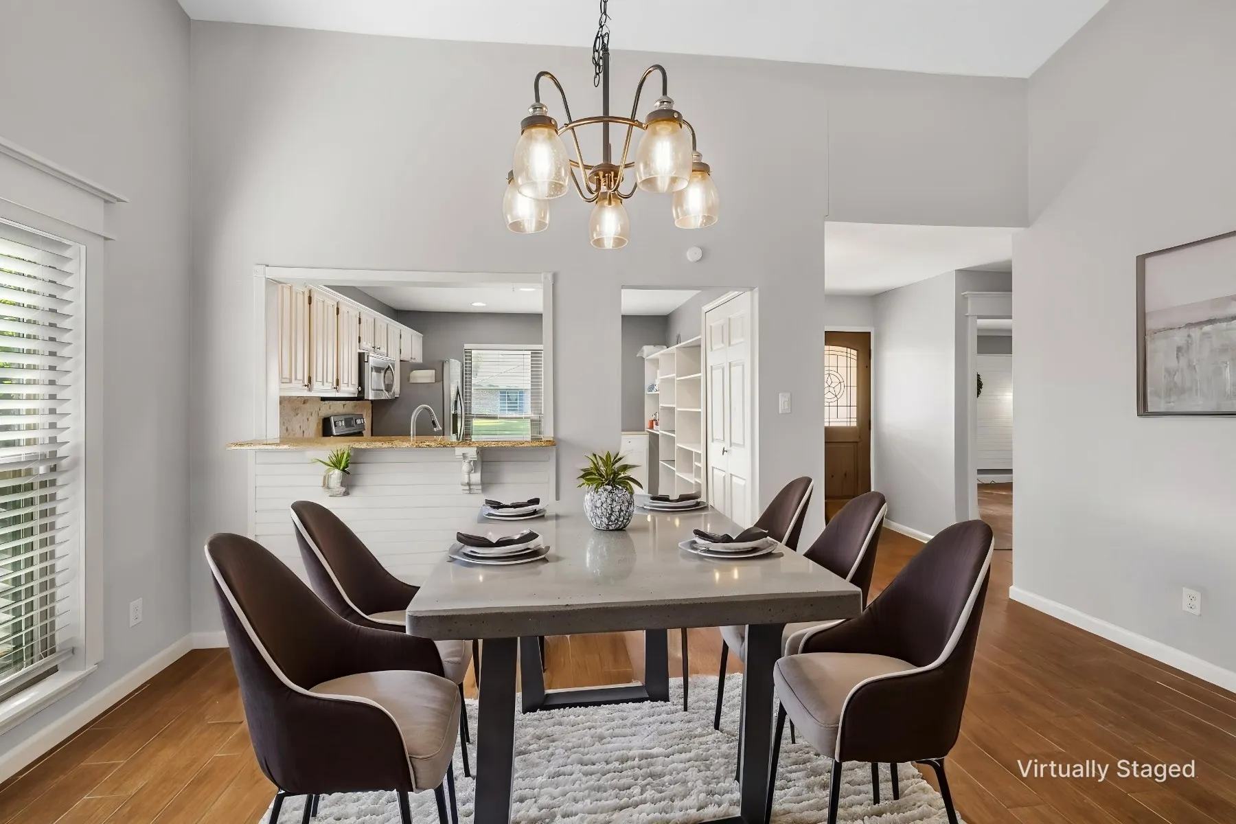 Virtually Staged photo showcasing what the dining room could look like. LVP wood-finish flooring, and a pass-through window to the kitchen.