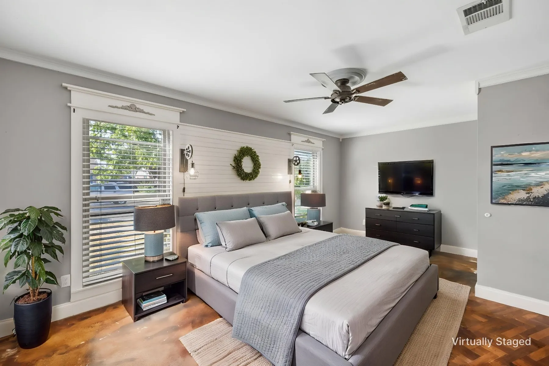 Virtually staged photo - primary bedroom with stained concrete flooring, windows, and shiplap accent wall.