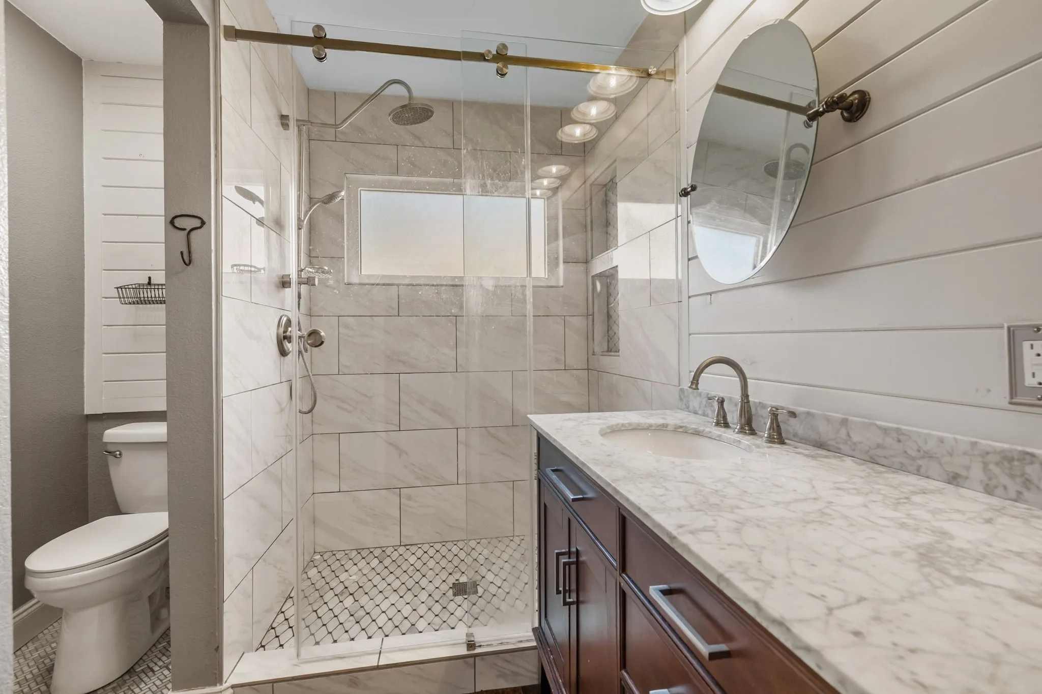 Glass-enclosed walk-in shower with subway tile surround, mosaic tile flooring, dual sinks, and integrated window