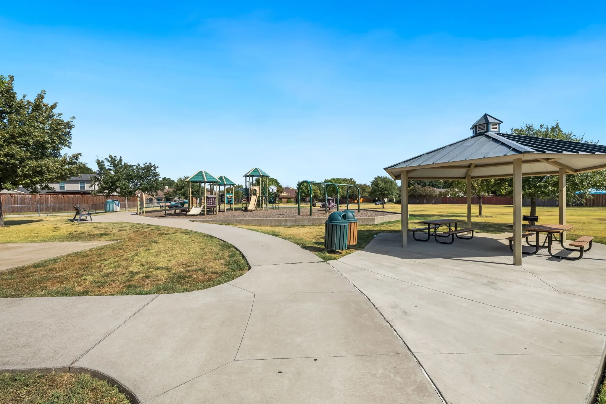Friendship Park is just a short walk down the street. Paved walkway leading to a playground area with a covered gazebo, picnic tables, and a basketball court.