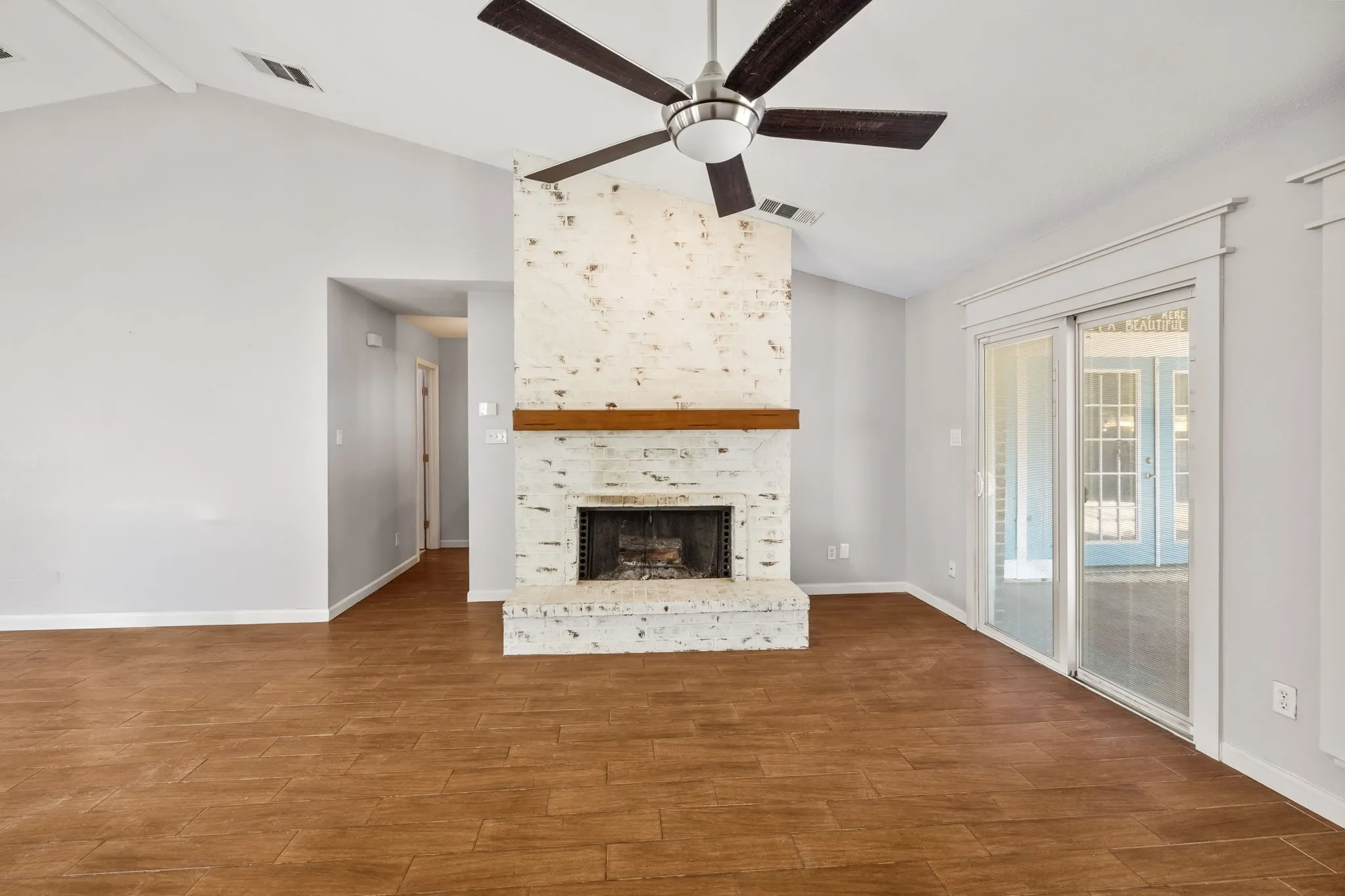 Living room with brick wood burning fireplace. Sliding glass door leads to oversized covered patio.