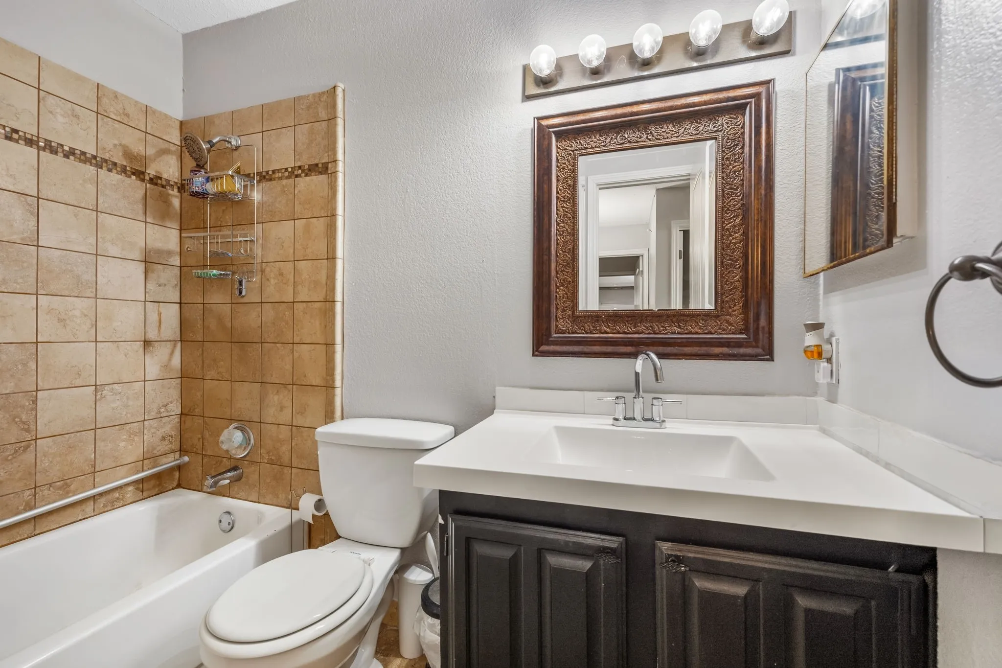 Hall bathroom featuring tub/shower combination with tiled surround and medicine cabinet.