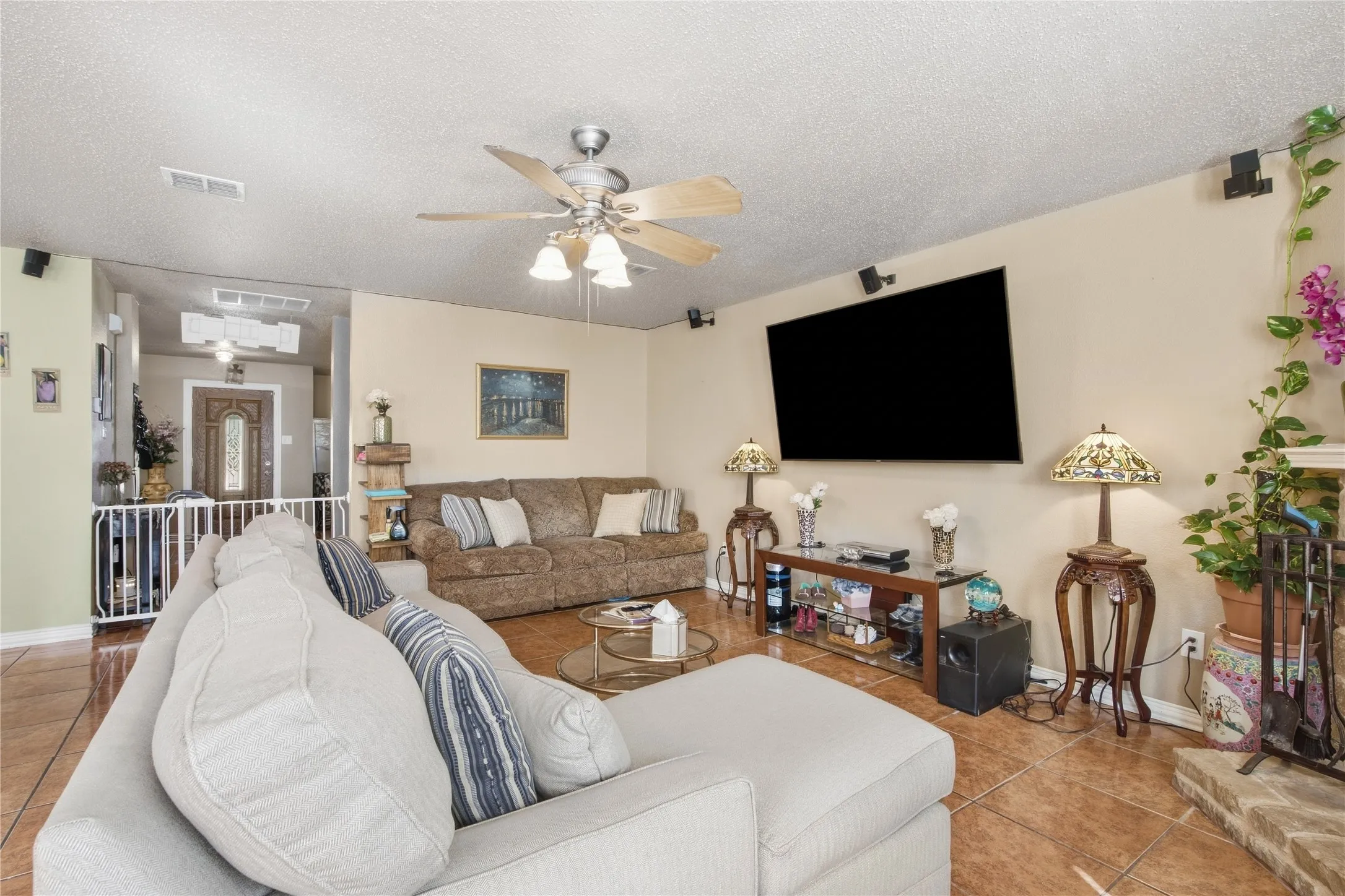 Spacious living area featuring tile flooring, a built-in entertainment niche, and a ceiling fan