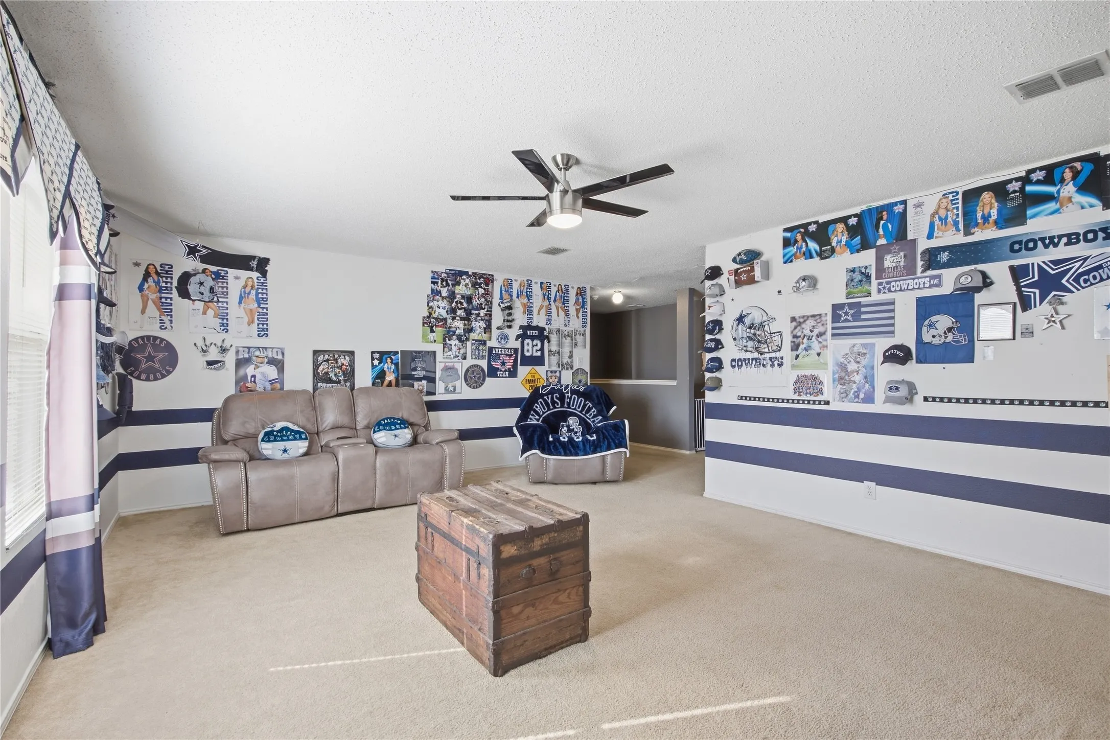 Carpeted room featuring a ceiling fan with light fixture