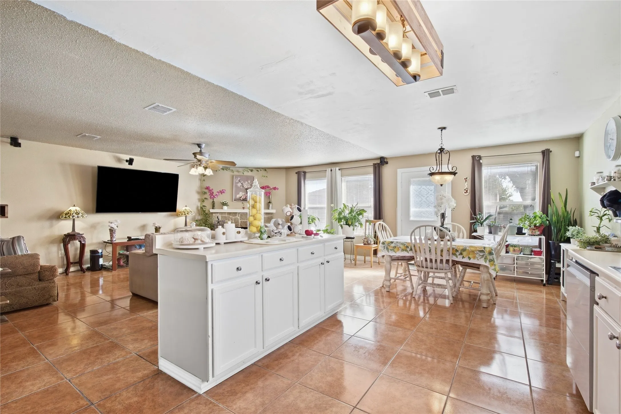 Open-concept living area featuring a kitchen island, tile flooring, and multiple windows