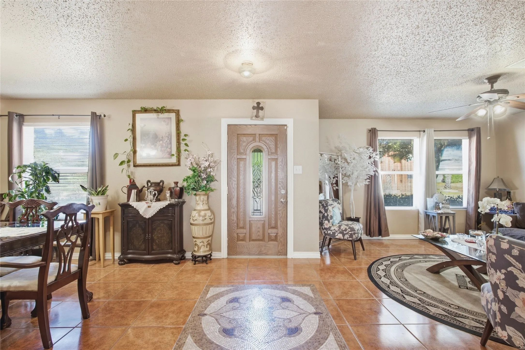 Tiled flooring throughout, decorative front entry door with leaded glass, recessed lighting, and a ceiling fan with integrated lighting