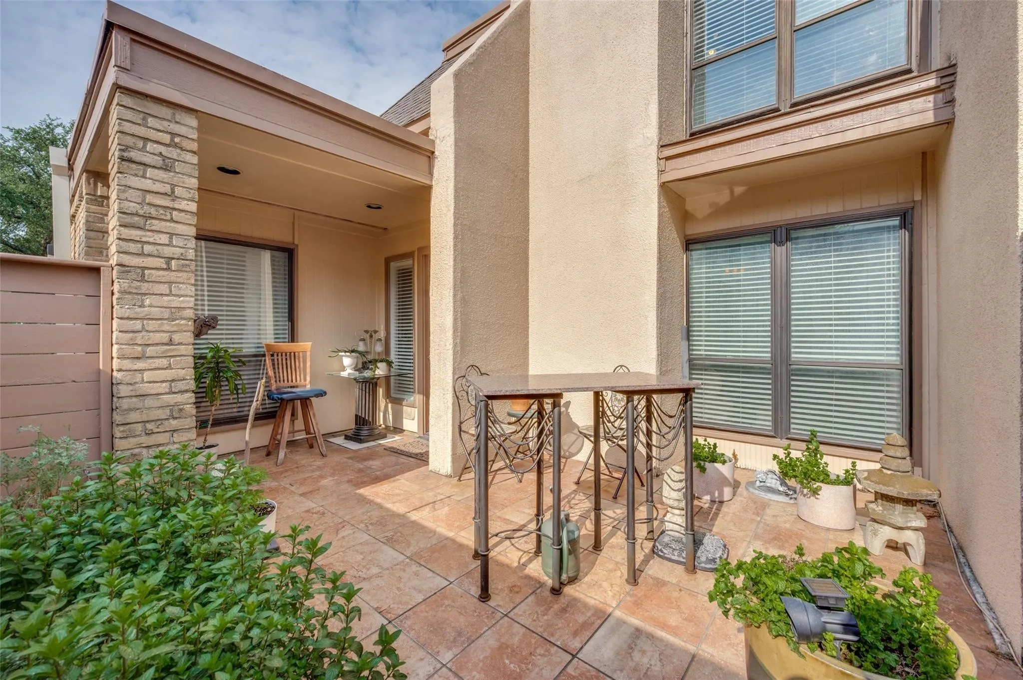 Paved patio featuring a partially covered entry with a brick column and a privacy fence