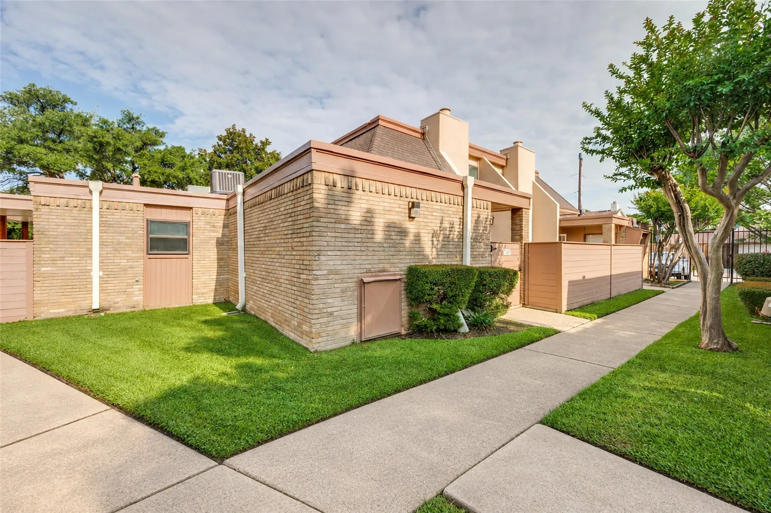 Brick exterior, concrete pathways, mature trees, and landscaping