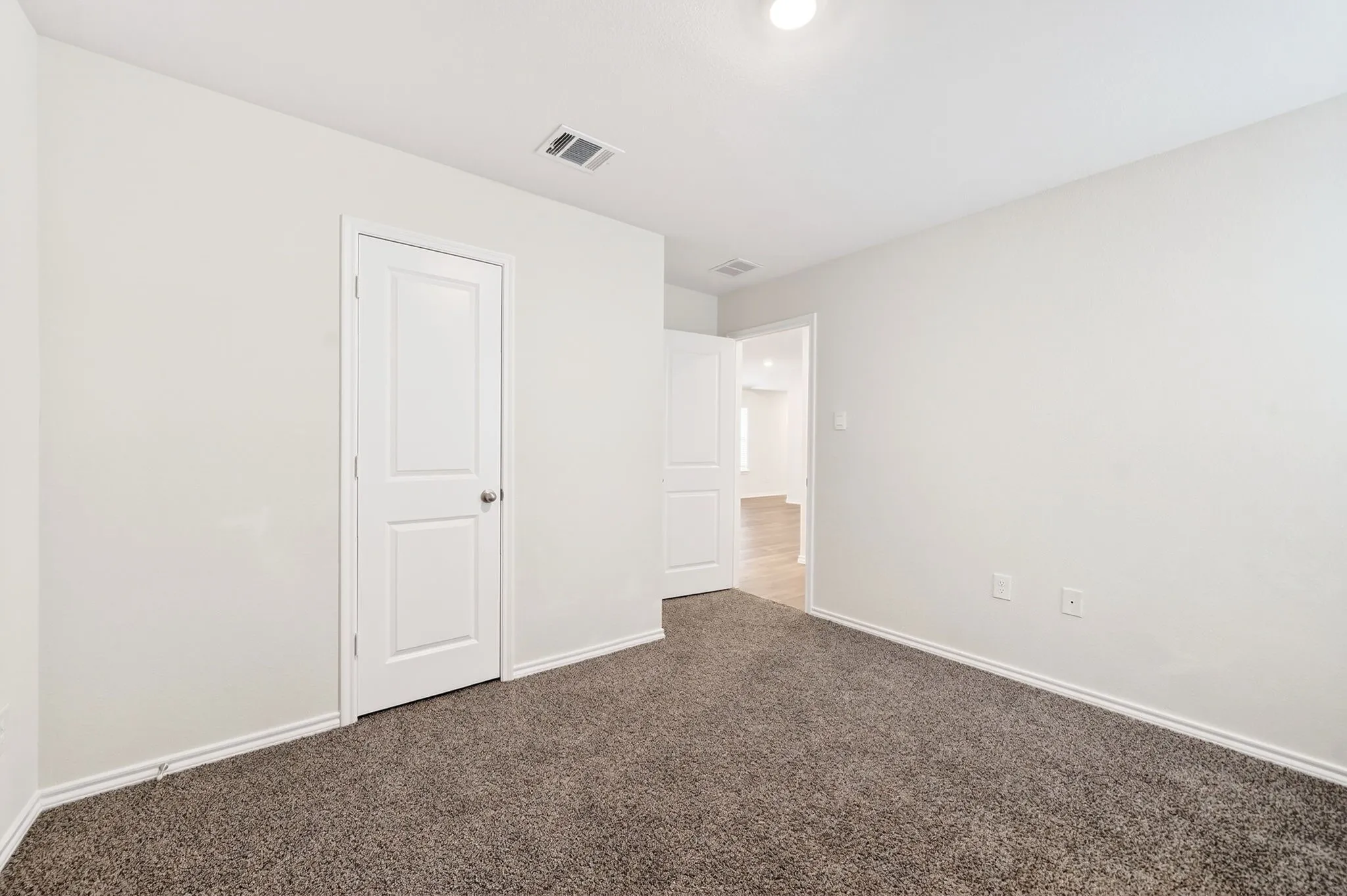 Neutral white walls, plush brown carpet, and a white paneled interior door