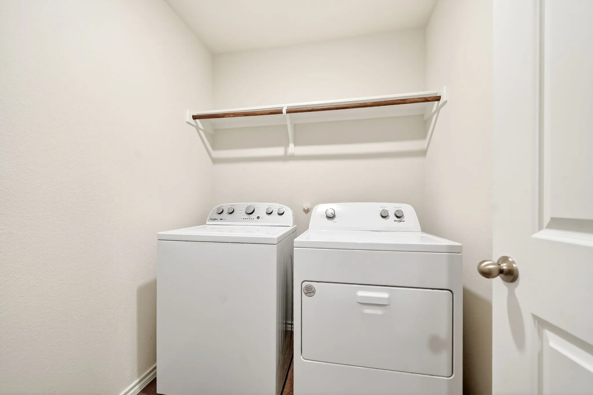 Built-in shelving with hanging rod, wood-finish flooring, and white interior door with brushed nickel hardware
