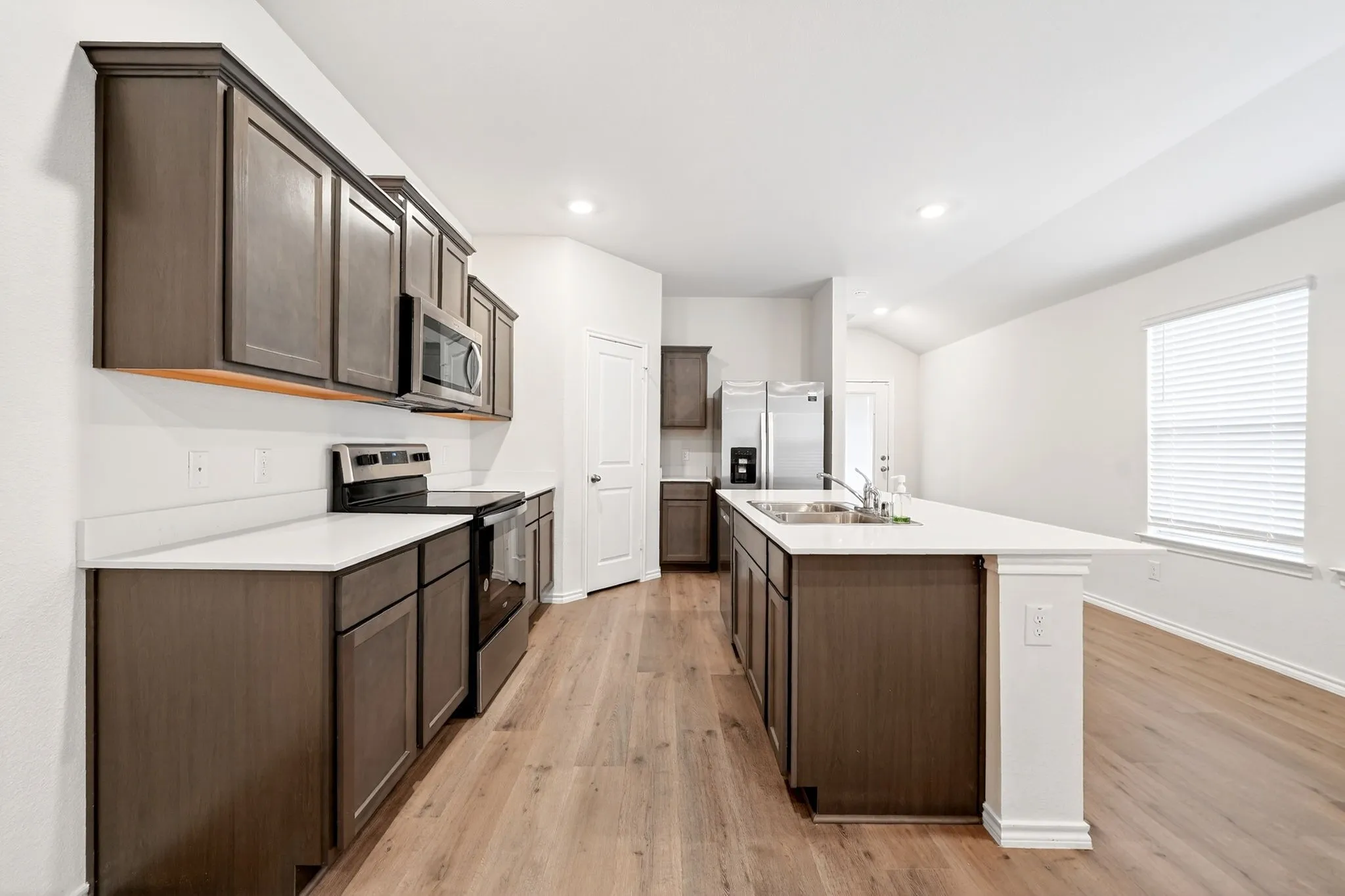 Kitchen with wood-finish flooring, dark wood-finish cabinetry, and stainless steel appliances