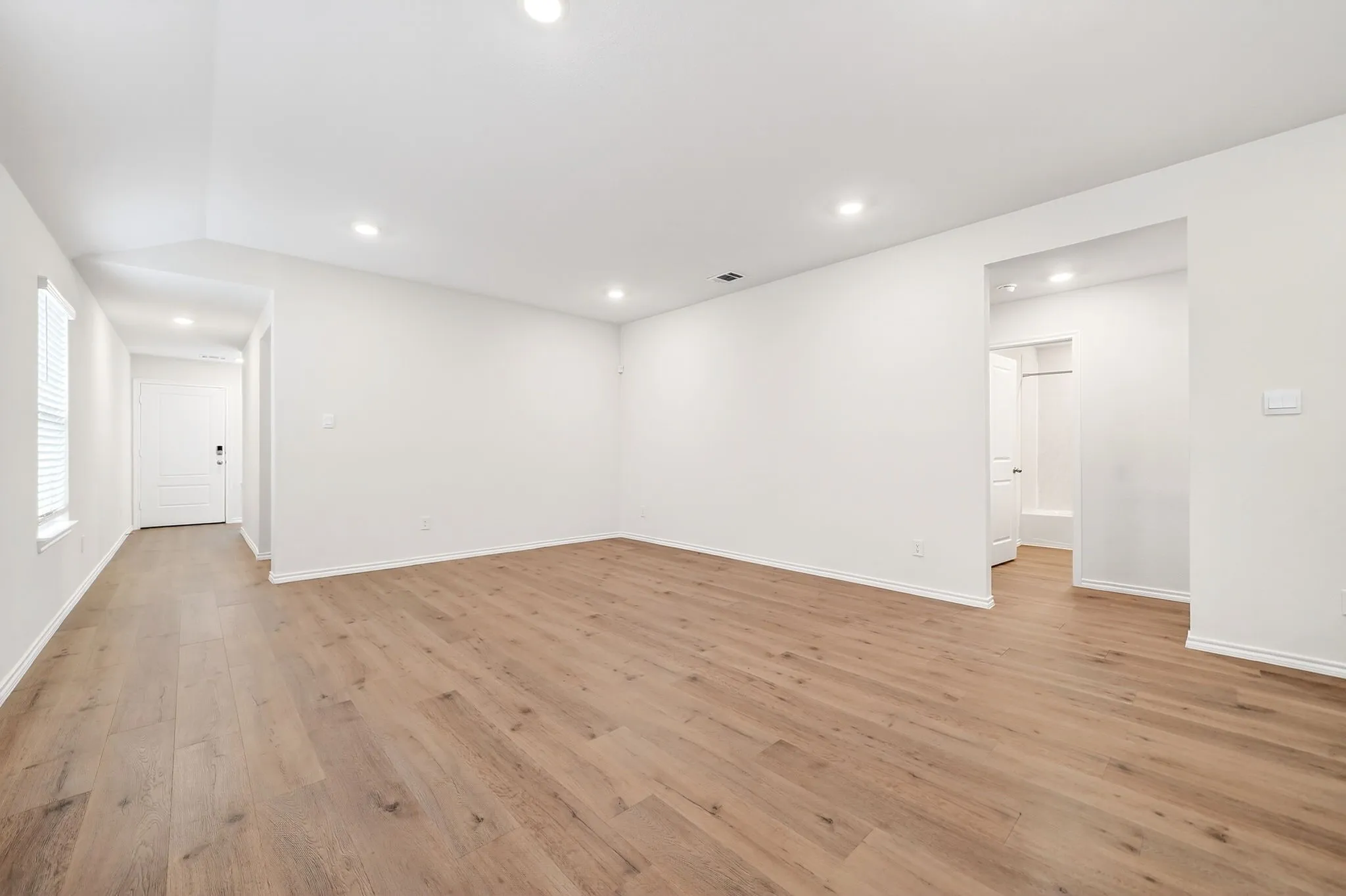 Spacious room with wood-finish flooring, recessed lighting, and white walls