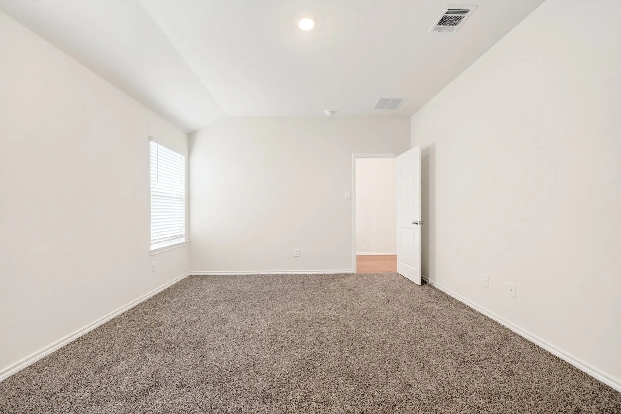 Neutral wall paint, plush carpet flooring, recessed ceiling lighting, window with blinds, and white interior door