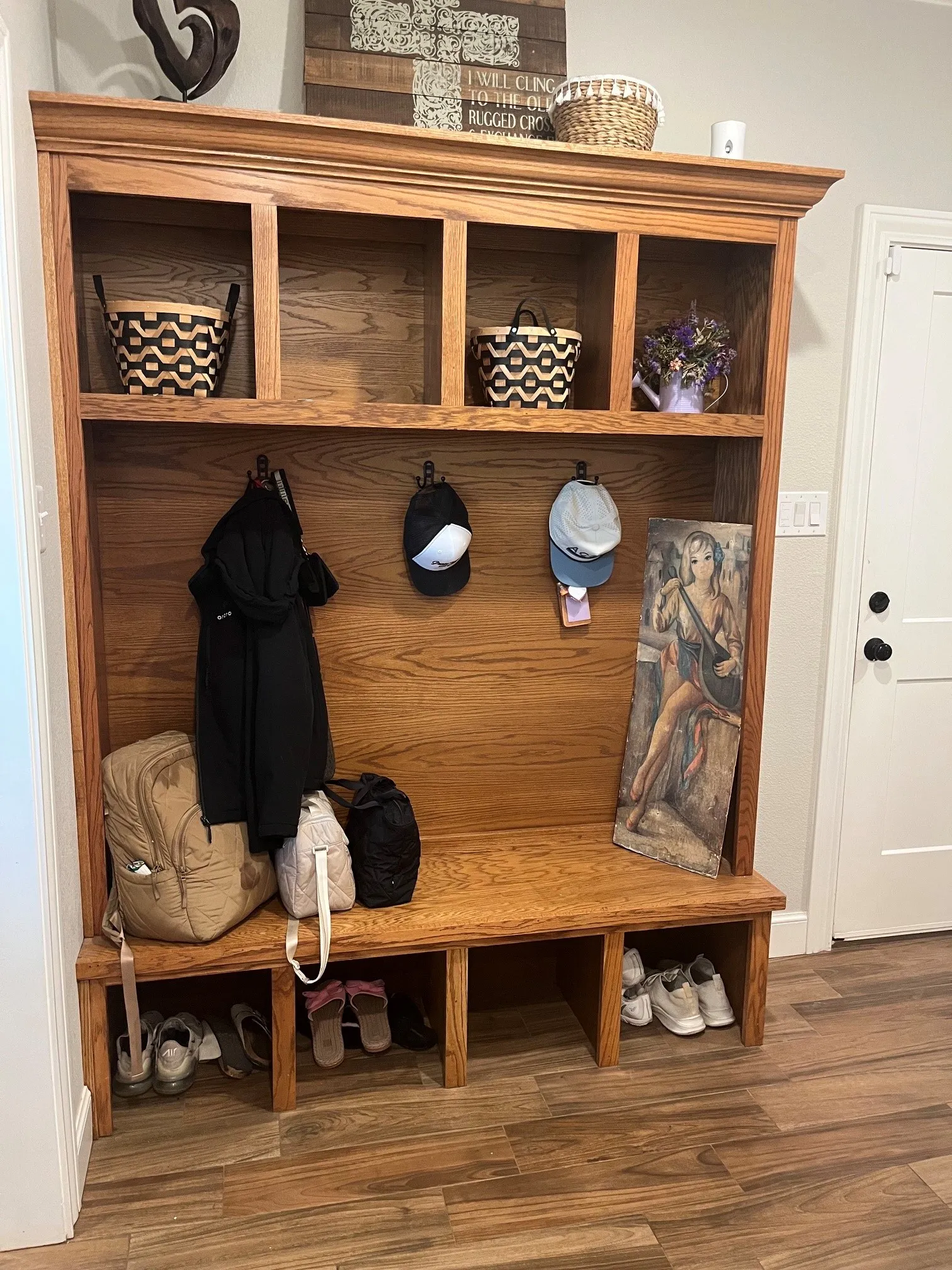 Built-in wooden hall tree with upper cubbies, coat hooks, and integrated lower bench with shoe storage