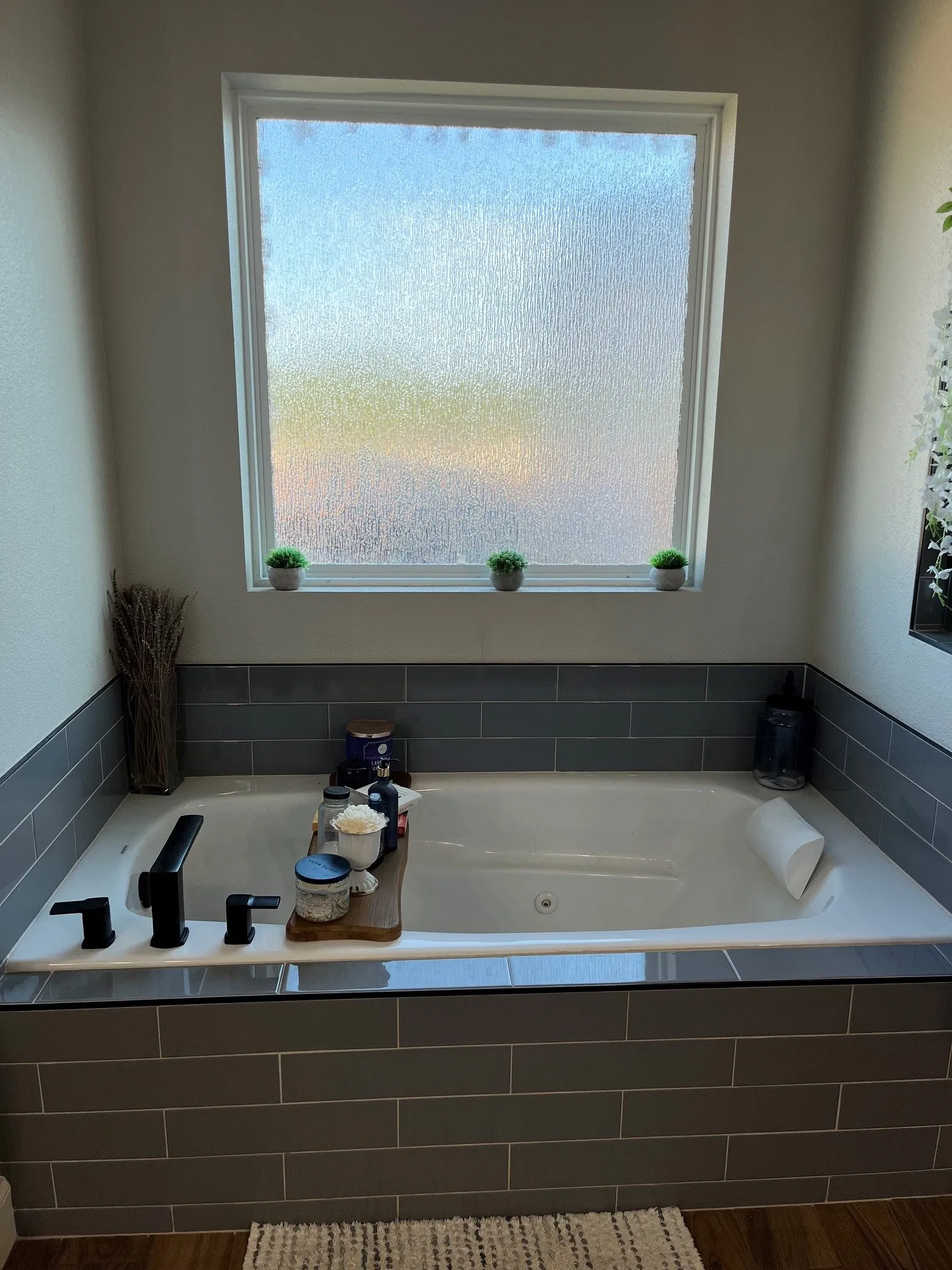 Built-in soaking tub with matte black fixtures, surrounded by gray subway tile