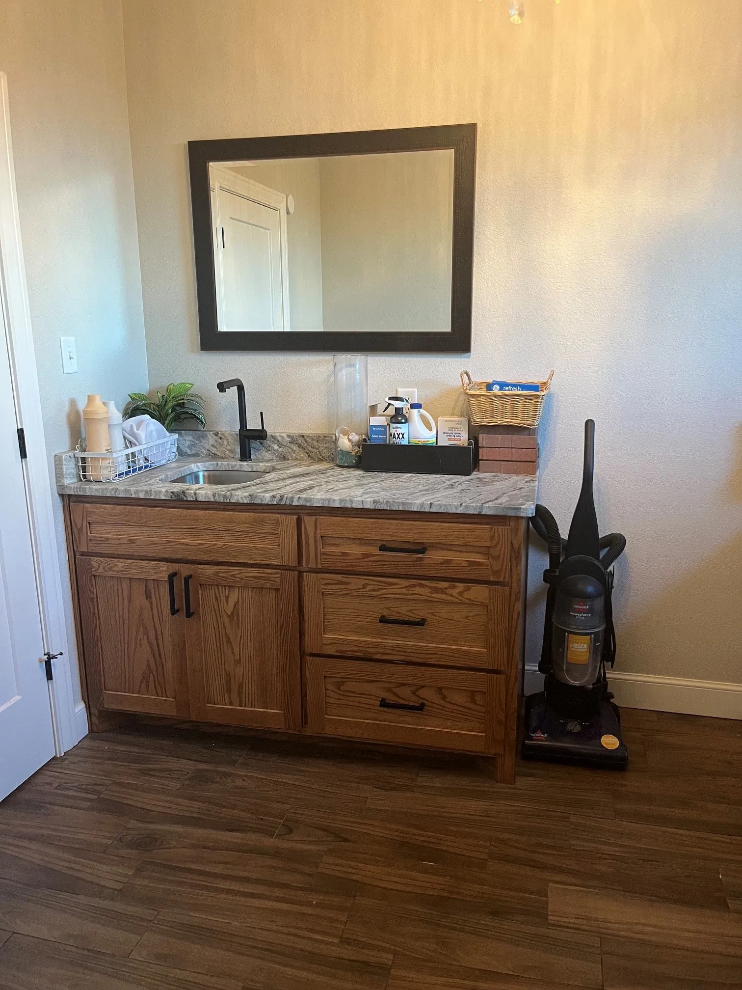 Wood-finish flooring, custom wood cabinetry with ample storage, integrated sink, and granite-style countertop