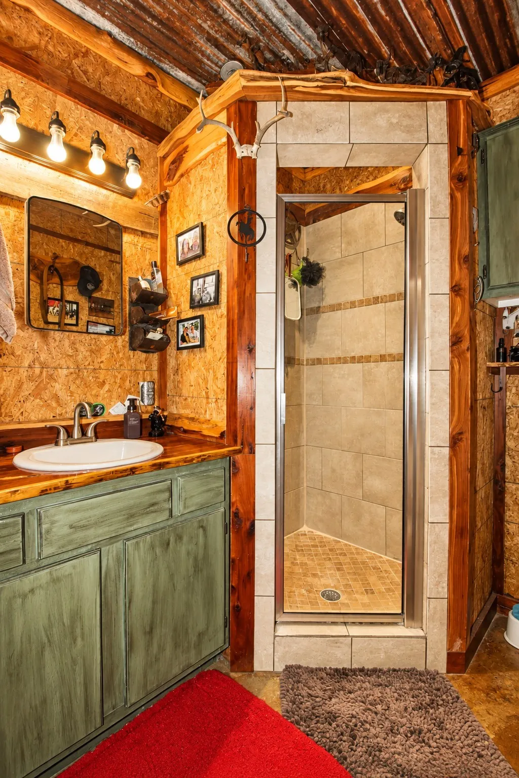 Wood-finish wall paneling, custom wood vanity with integrated sink, tile-surround shower with glass enclosure, wood-clad ceiling, and overhead vanity lighting