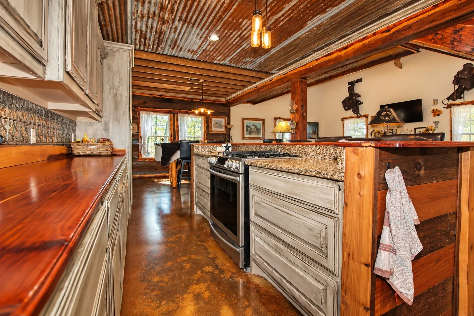Kitchen with wood-finish countertops, grey cabinetry, stainless steel range, textured tile backsplash, and a corrugated metal ceiling