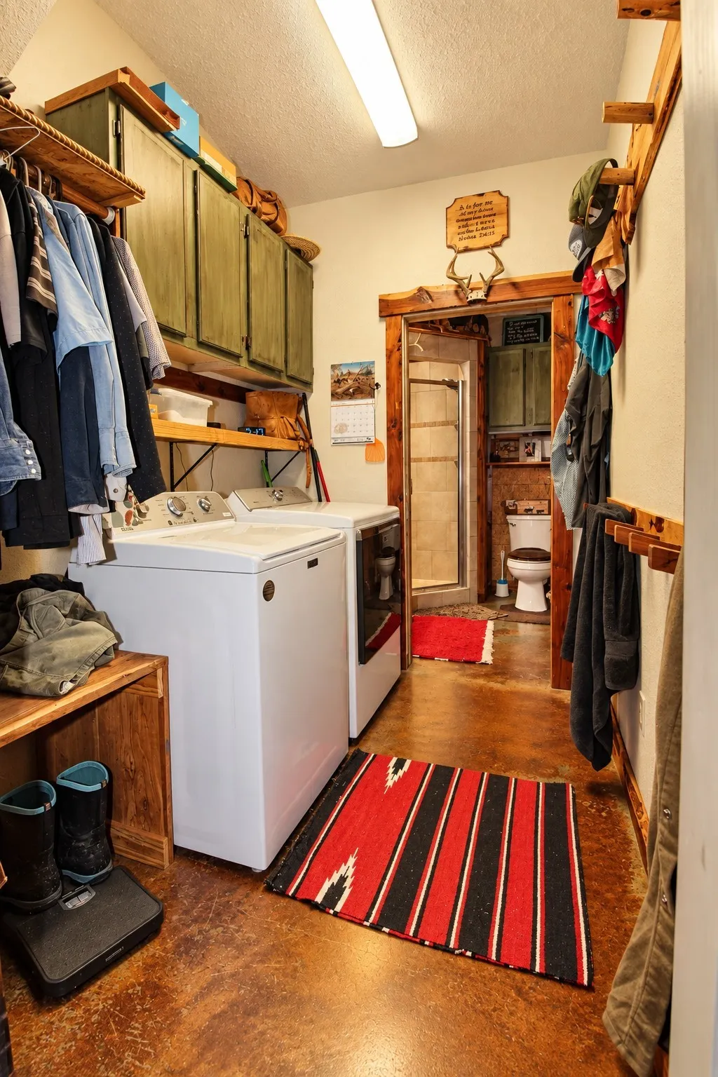 Laundry area with built-in upper cabinetry, wood-finish shelving, and stained concrete flooring