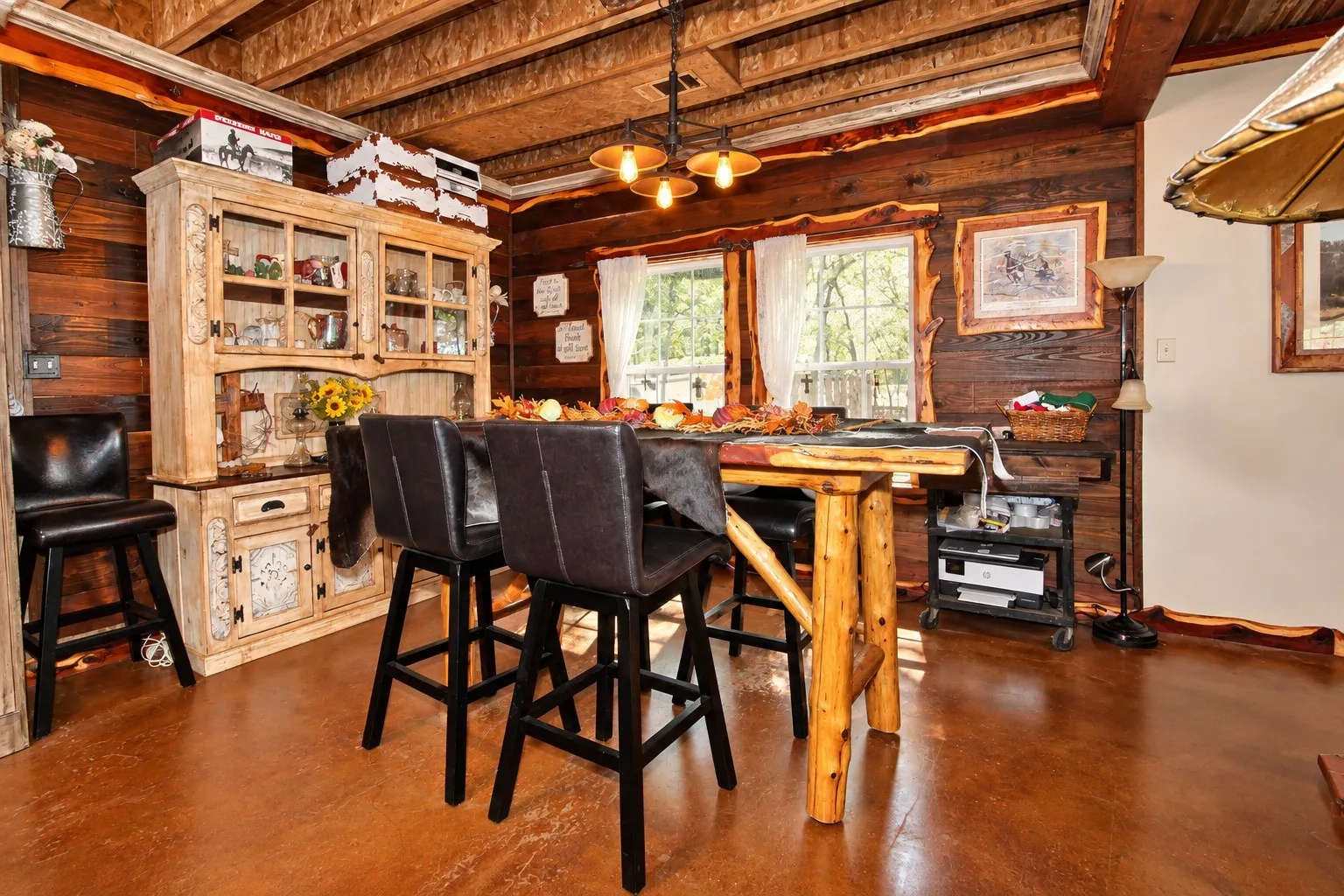 Wood-finish flooring, exposed wood beam ceiling, wood-paneled walls, built-in display hutch, and multiple windows