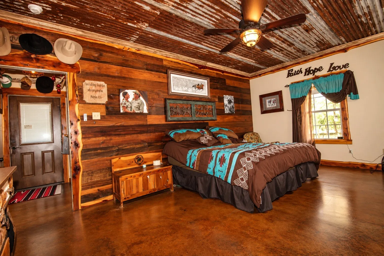Wood-paneled wall, corrugated metal ceiling, ceiling fan with integrated lighting, wood-finish flooring, and a large window providing natural illumination
