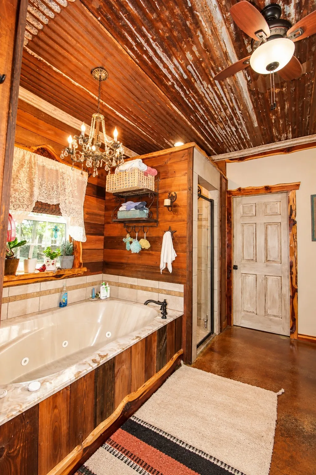 Jetted soaking tub with wood-finish paneling, tiled surround, and dark bronze fixtures