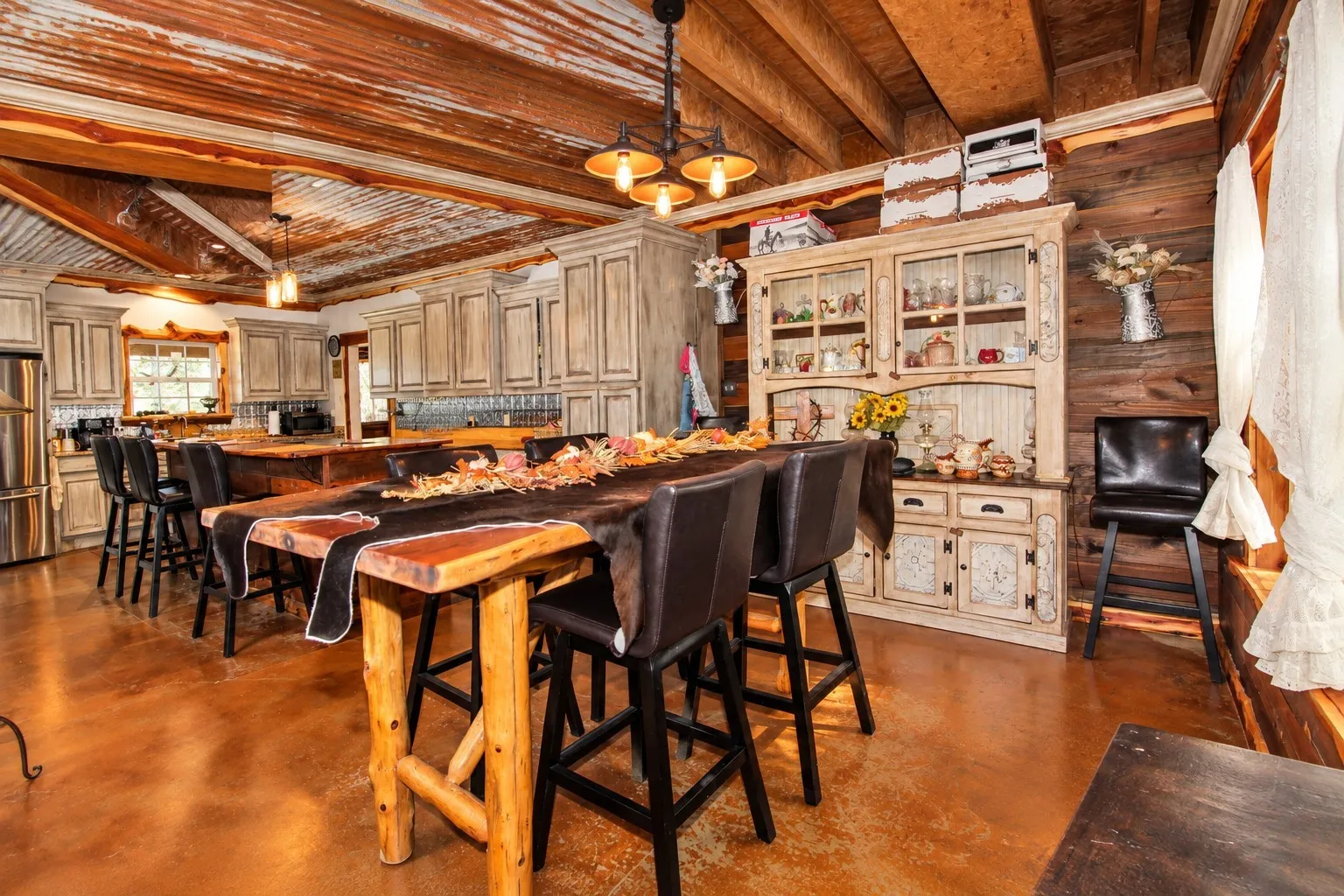 Wood plank walls, wood-finish flooring, wood beam ceiling, exposed corrugated metal ceiling, and built-in cabinetry