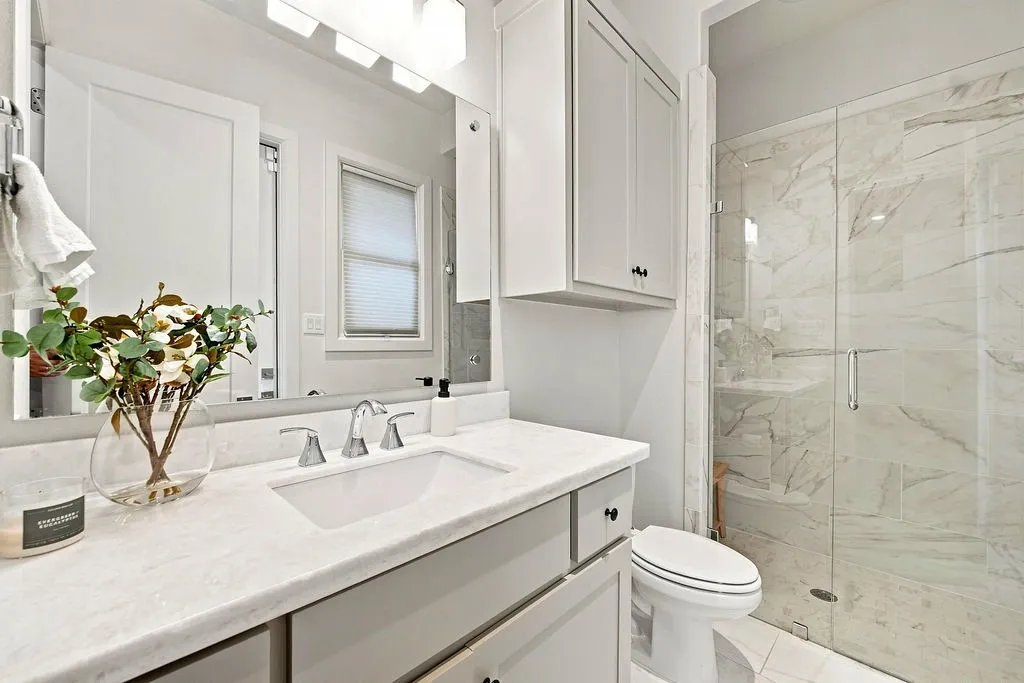 Beautiful tilework, a bright vanity, and a walk-in shower provide a welcoming space for visitors