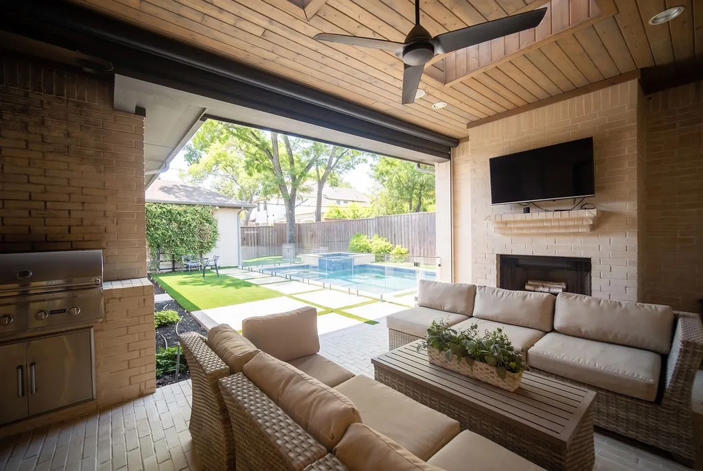 A towering stone fireplace and ceiling fan keep this outdoor living room cozy during chilly fall nights and cool during summer evenings