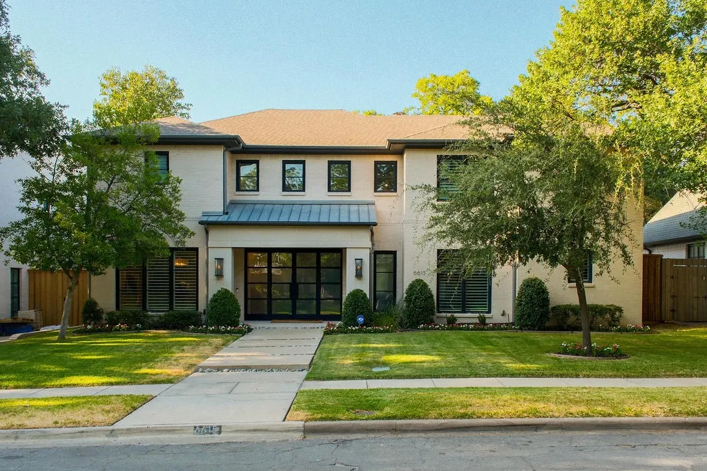 A inviting look at this exceptional single-family home in Preston Hollow, where mature trees frame a welcoming entrance that hints at the comfortable luxury found inside
