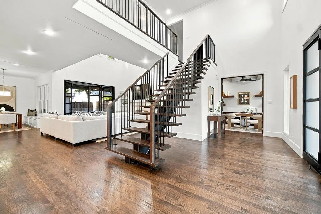 Warm wood floors and a custom floating staircase create an inviting entry where you can pause, drop your keys, and feel instantly at ease
