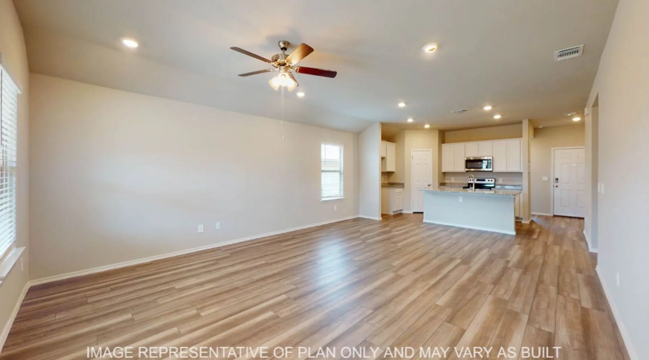 Expansive open-concept living area featuring wood-finish flooring, recessed lighting, and a ceiling fan