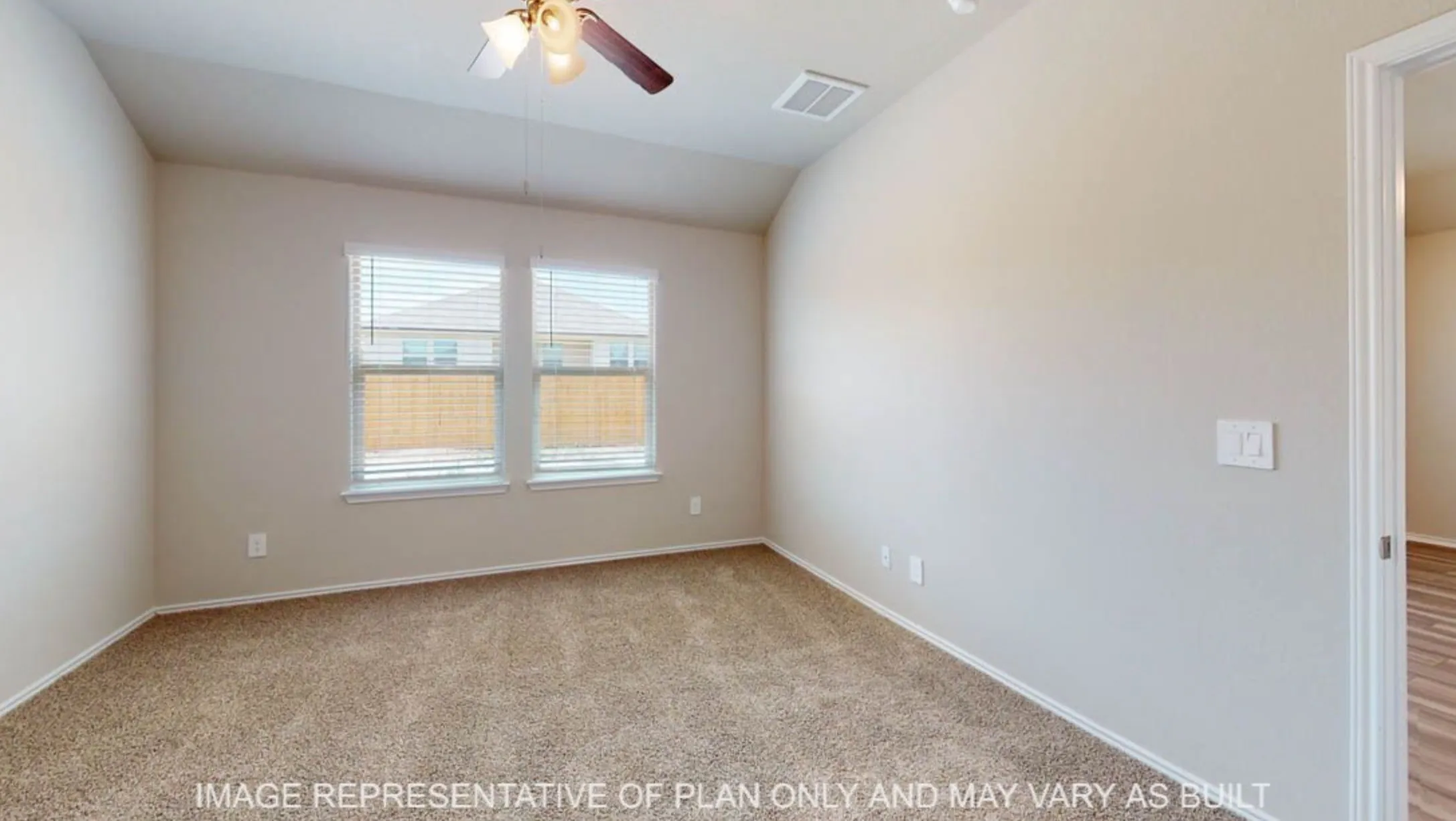 Bright secondary bedroom featuring carpet flooring, dual windows with plantation shutters, ceiling fan, and neutral wall finishes