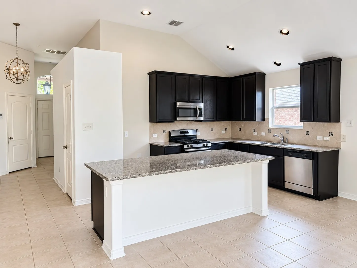 Kitchen featuring an island with a granite countertop, dark wood cabinetry, stainless steel appliances, and tile flooring