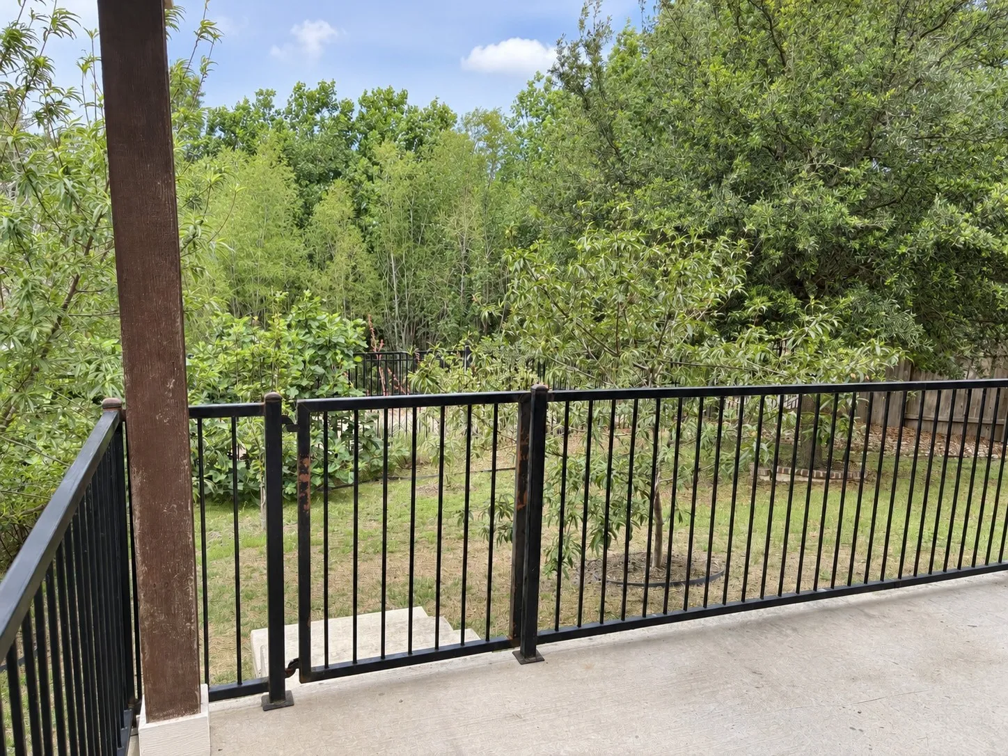 Concrete patio with black metal railing and gate