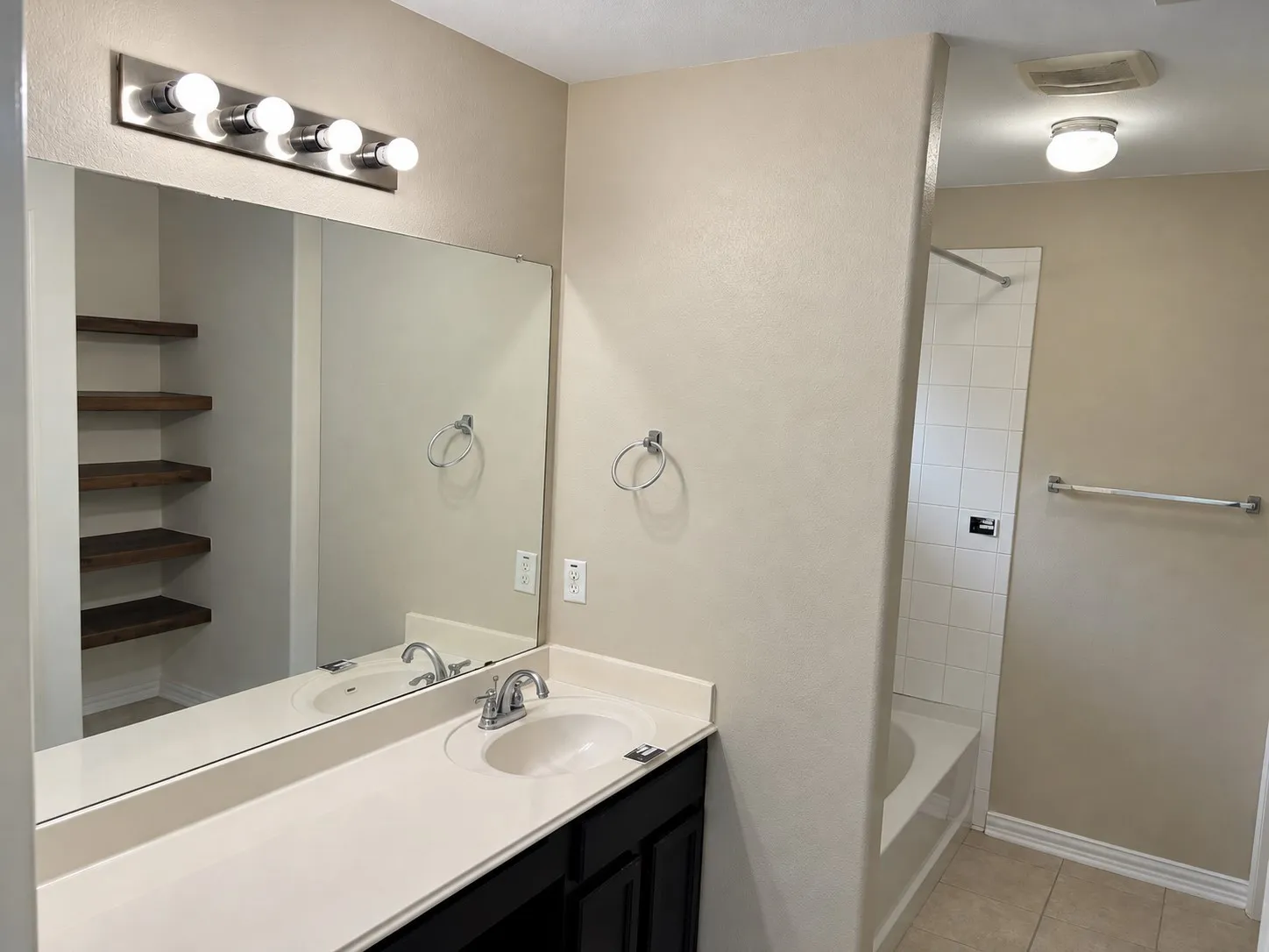 Vanity with integrated sink, chrome faucet, and expansive mirror