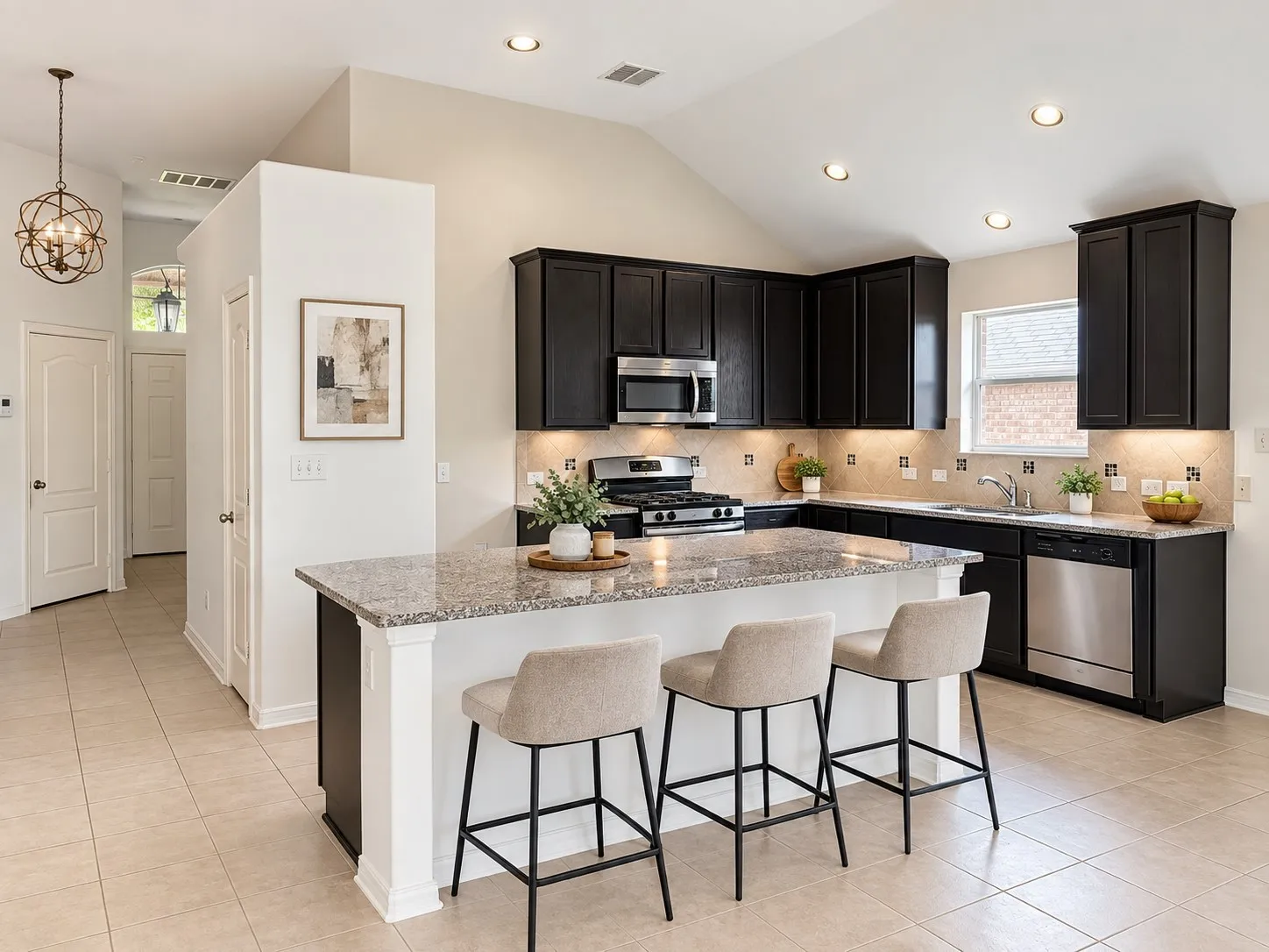 Kitchen featuring dark cabinetry, stainless steel appliances, an island with countertop seating, and tile flooring